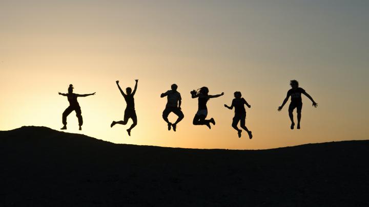 Ilmaan hyppääviä ihmisiä, jotka näkyvät siluettina auringonlaskun taivasta vasten