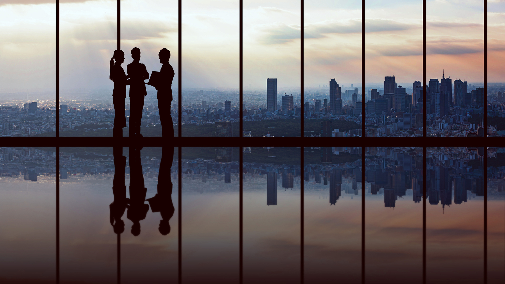 People discussing in front of a window of a skyscraper with a city scene on the background