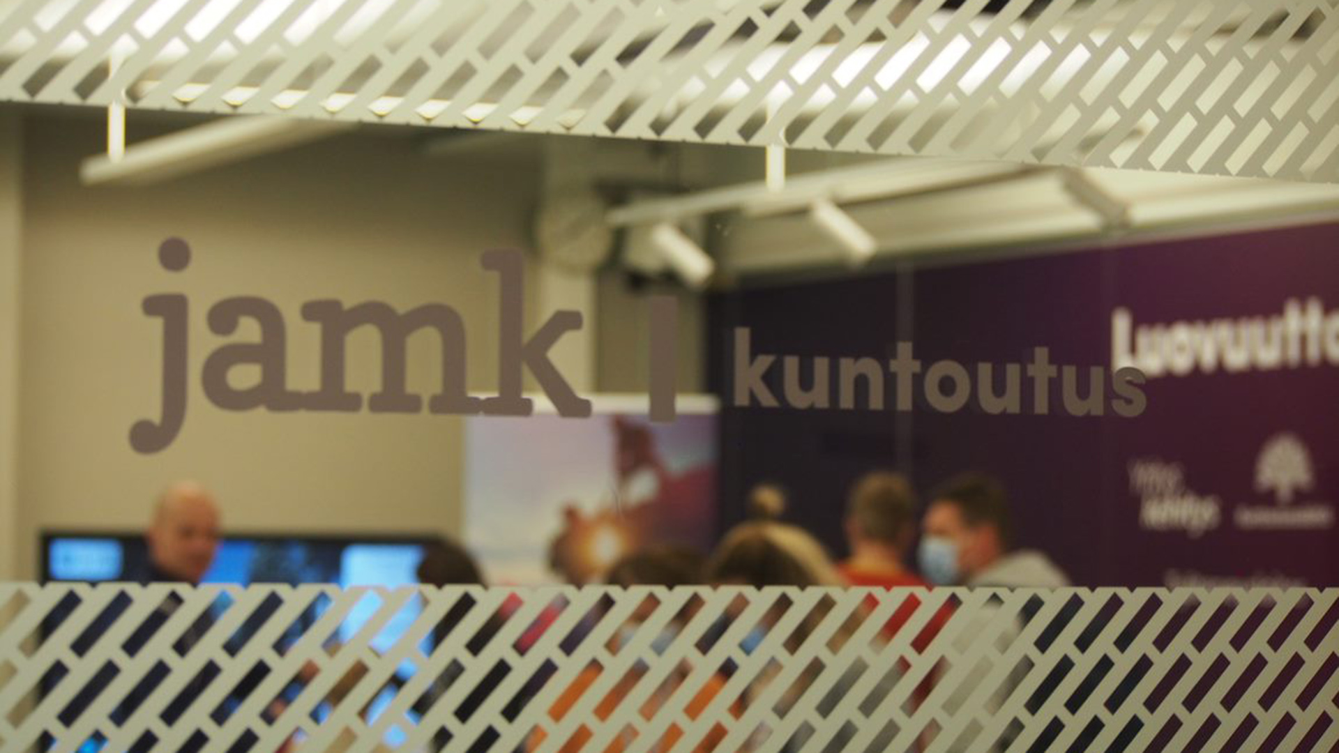 Ihmisiä ikkunan takana, jossa Jamk Kuntoutus-logo