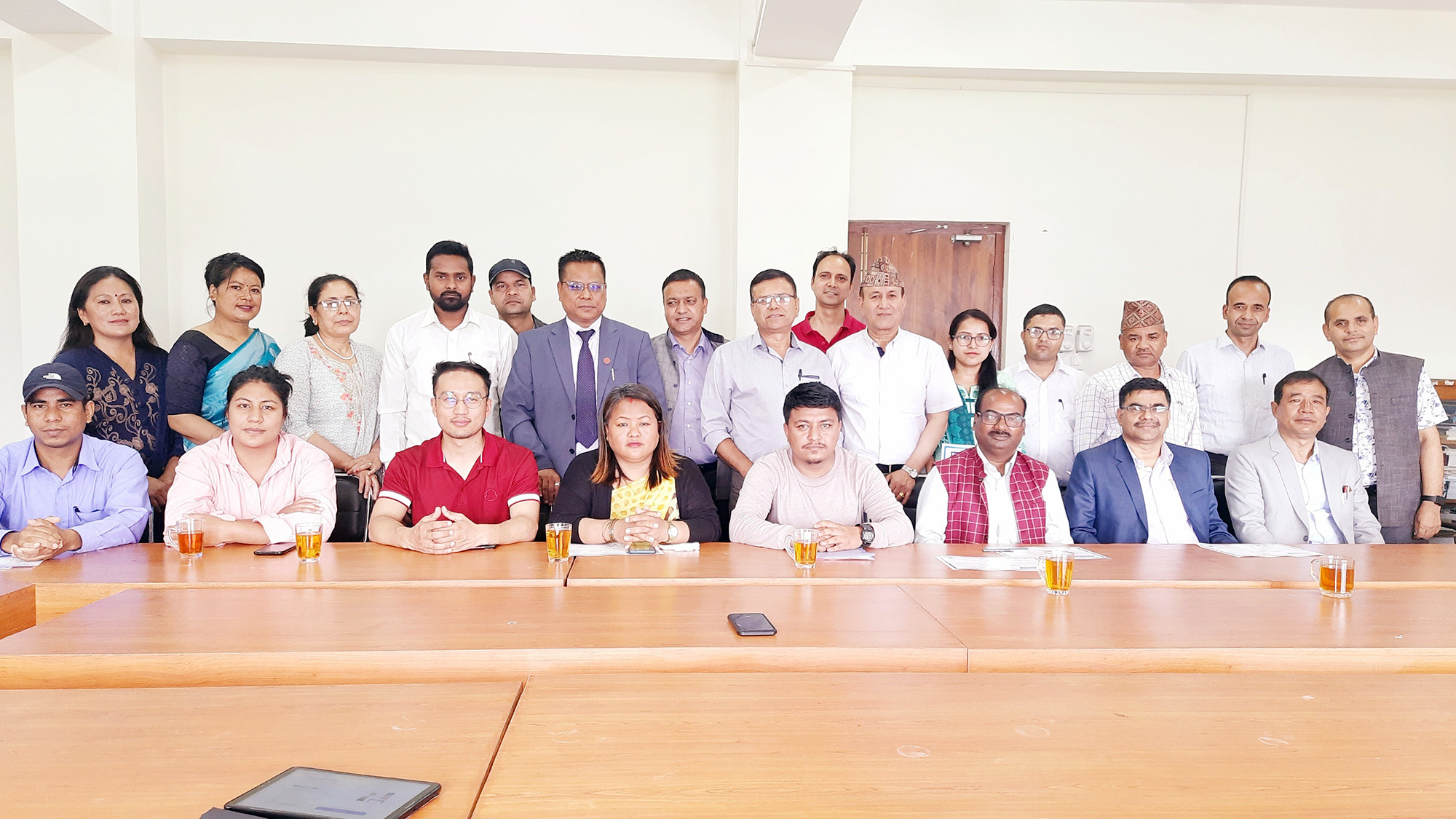 Nepalese training participants sitting and standing behind a conference room table