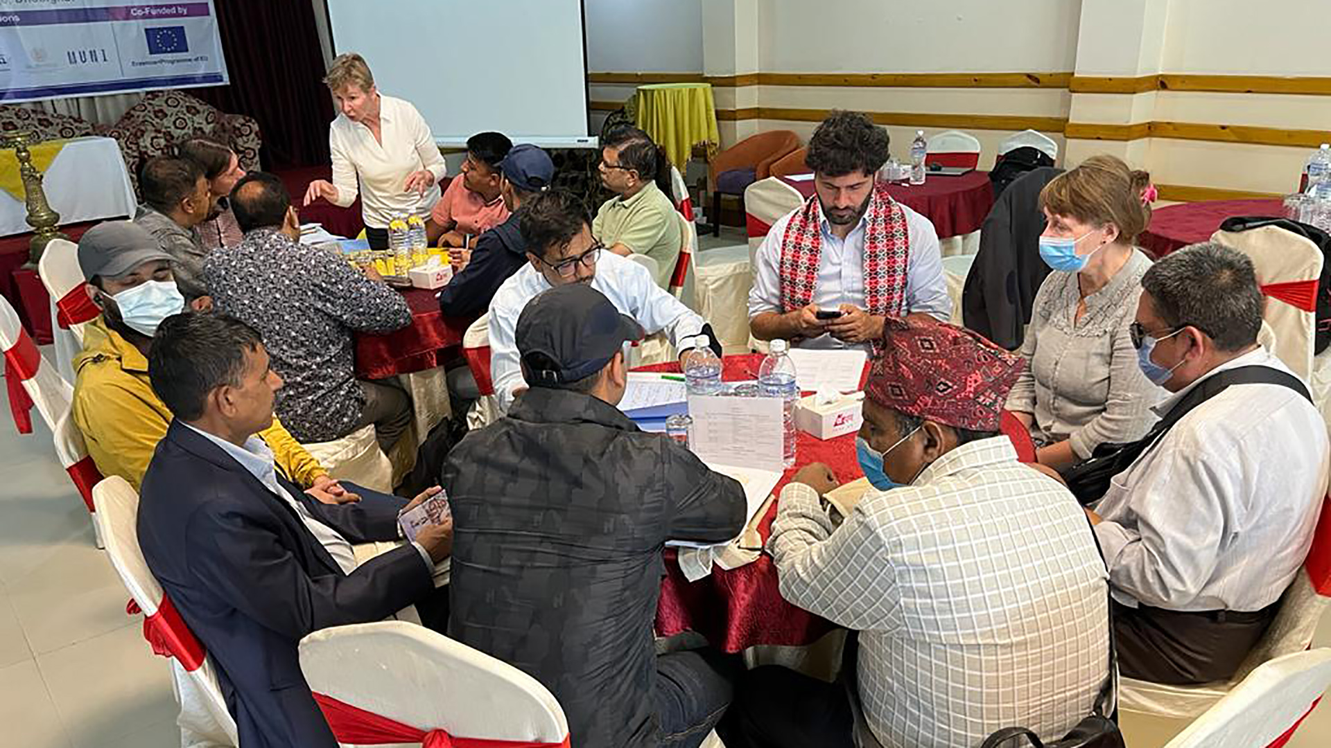 Over twenty people sitting and working by table at a seminar