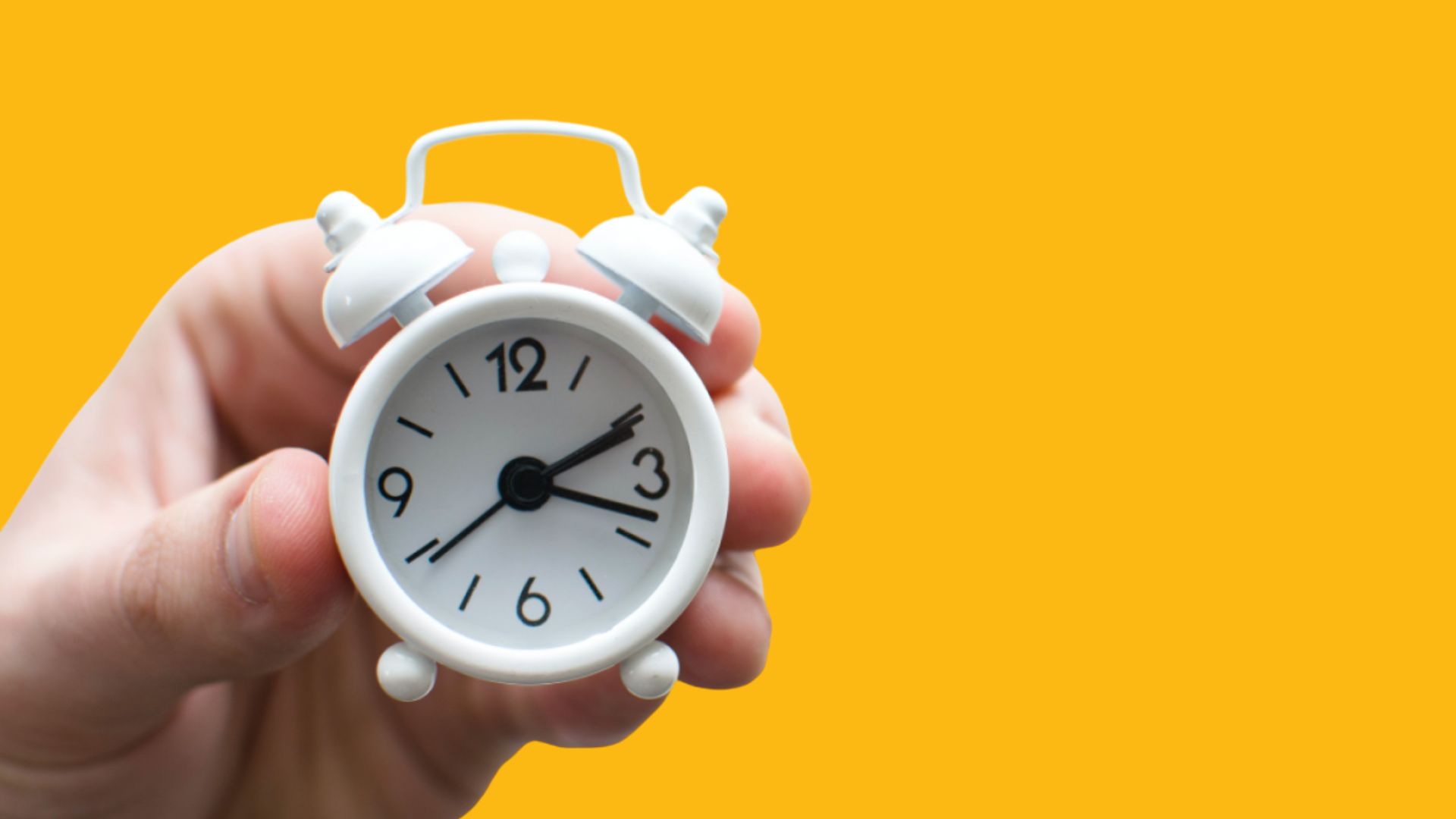 Käsi pitelee herätyskelloa.