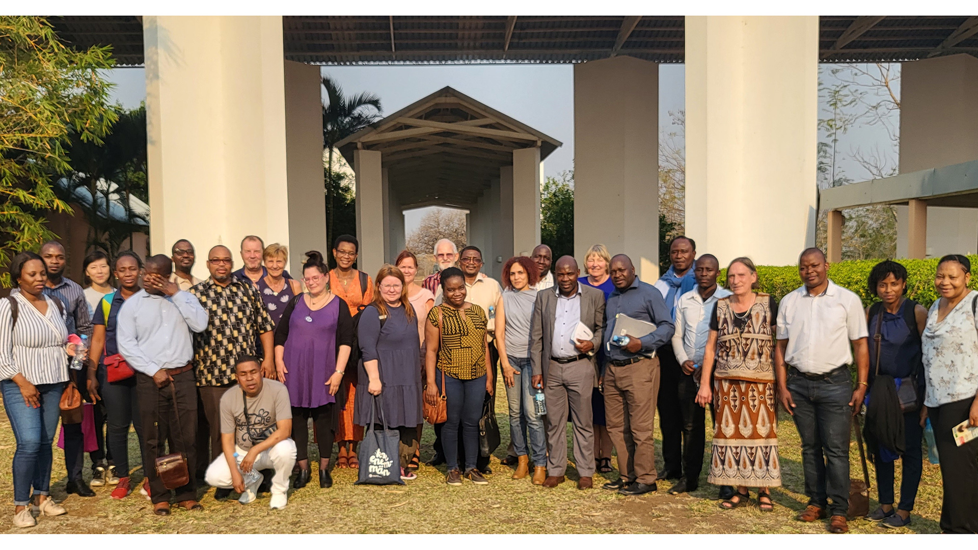 A large group of Mozambiqan and Finnish people standing outside a building in sunshine