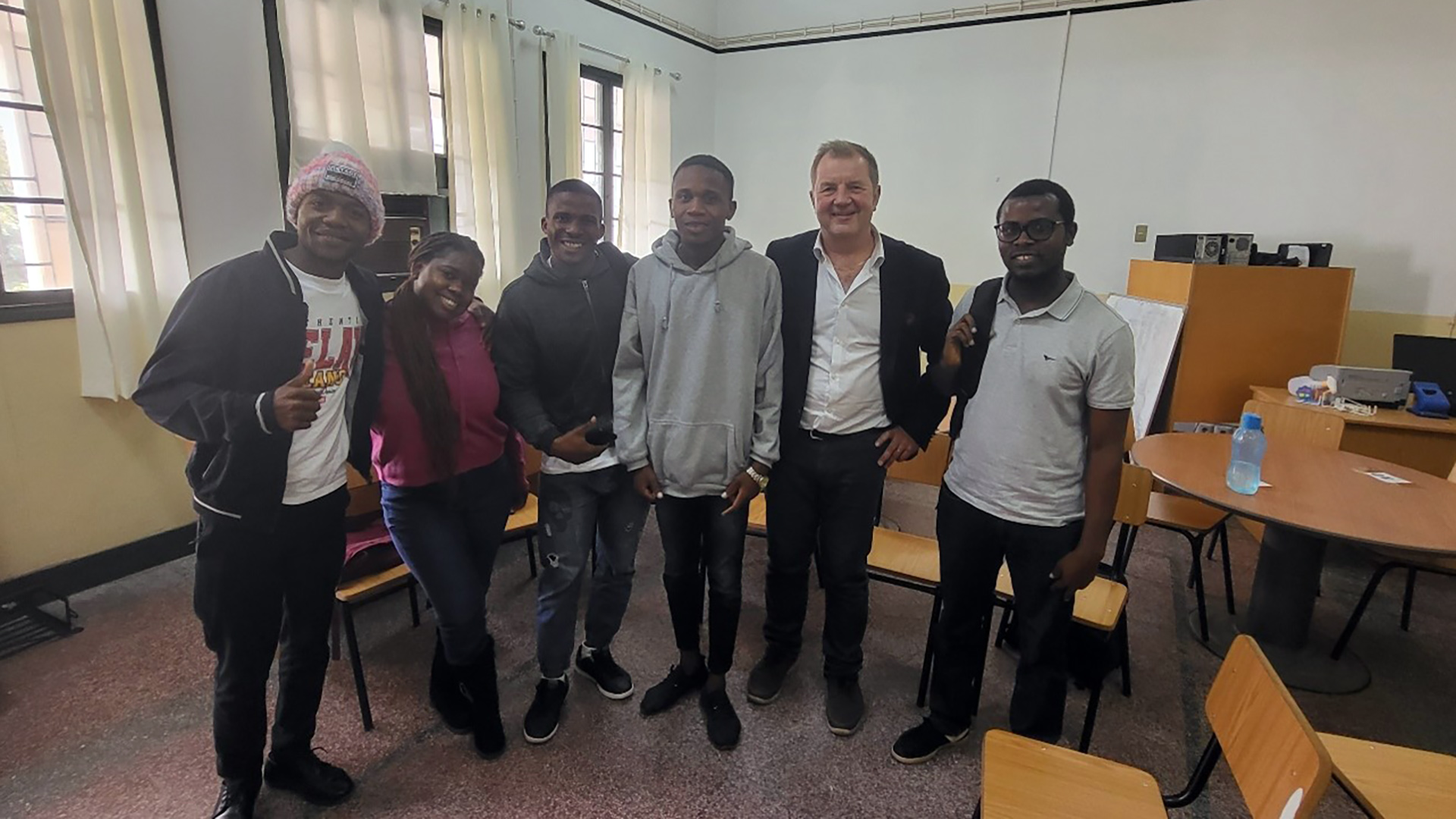Five Mozambican students with Juha Hautanen standing in a class room.