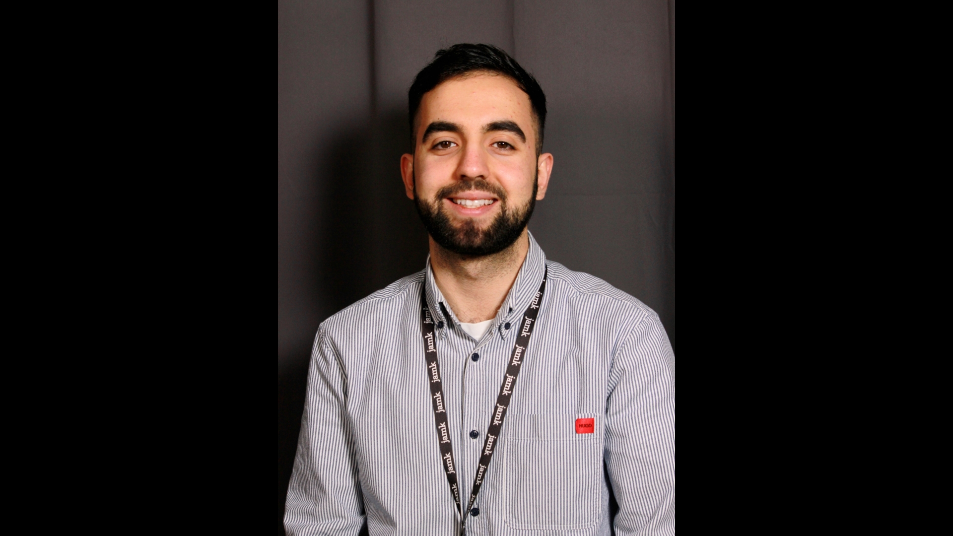 Aleksandr Dzharatov hymyilee tummalla taustalla