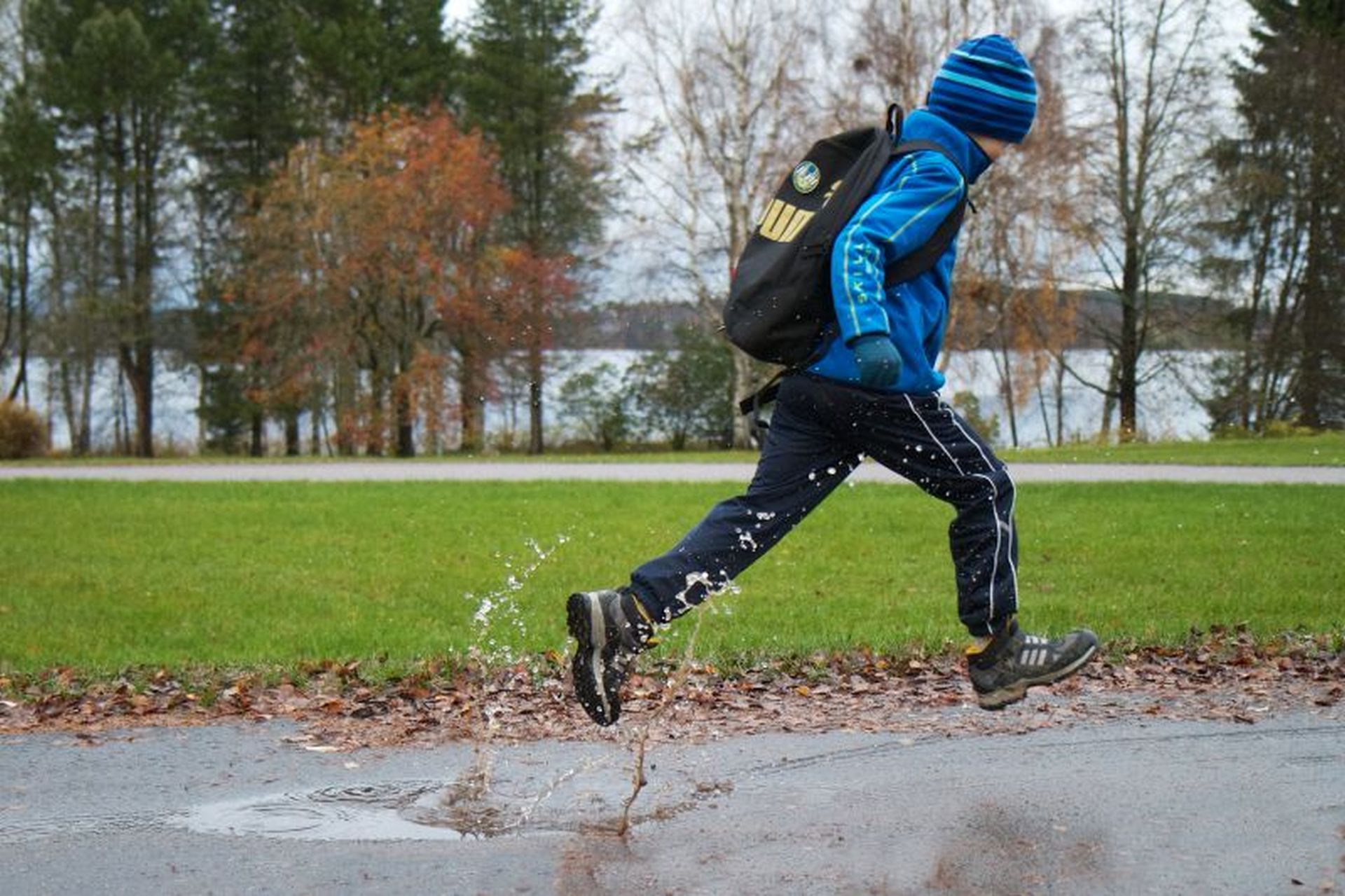 Lapsi juoksee vesisateella kävelytiellä.