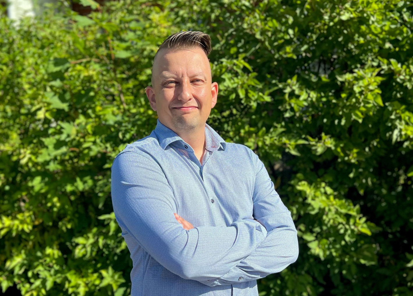 Pekka Anttila sinipaitainen mies, taustalla vihreitä kasveja