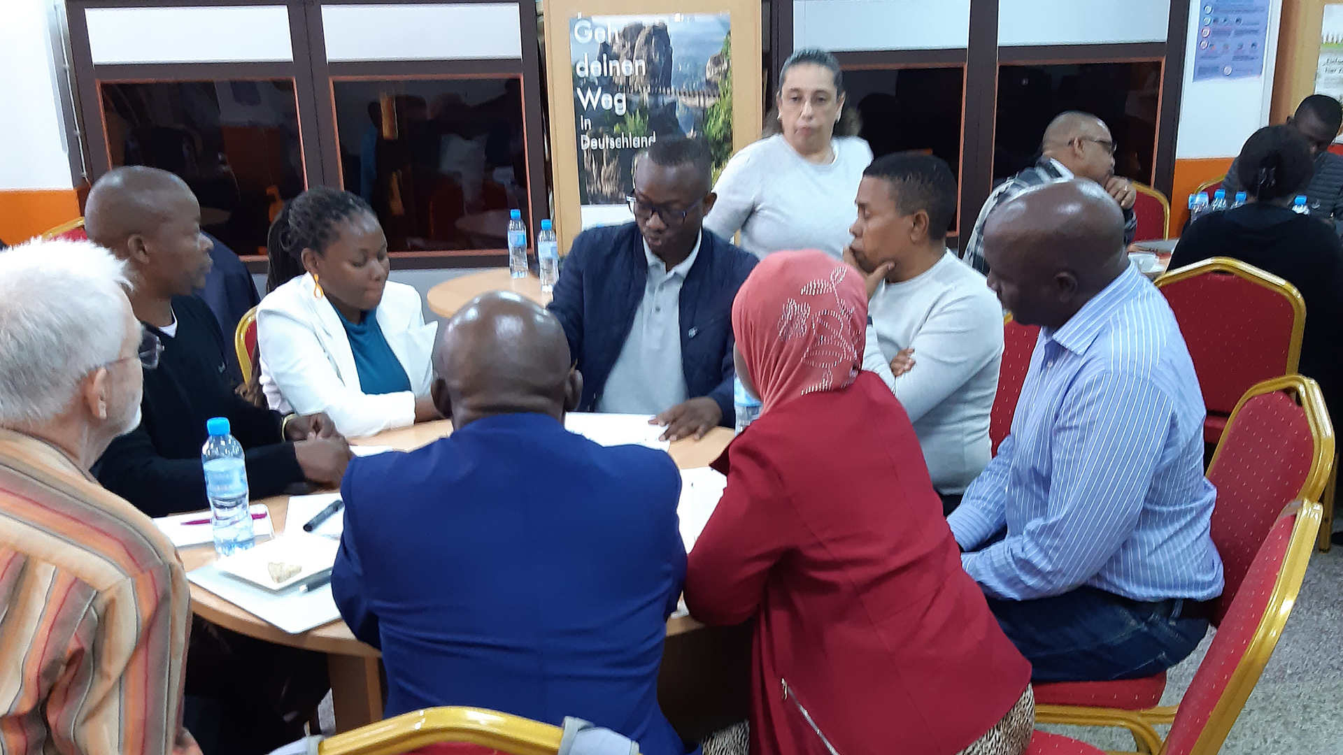 Over 10 people sitting and working together at a workshop.