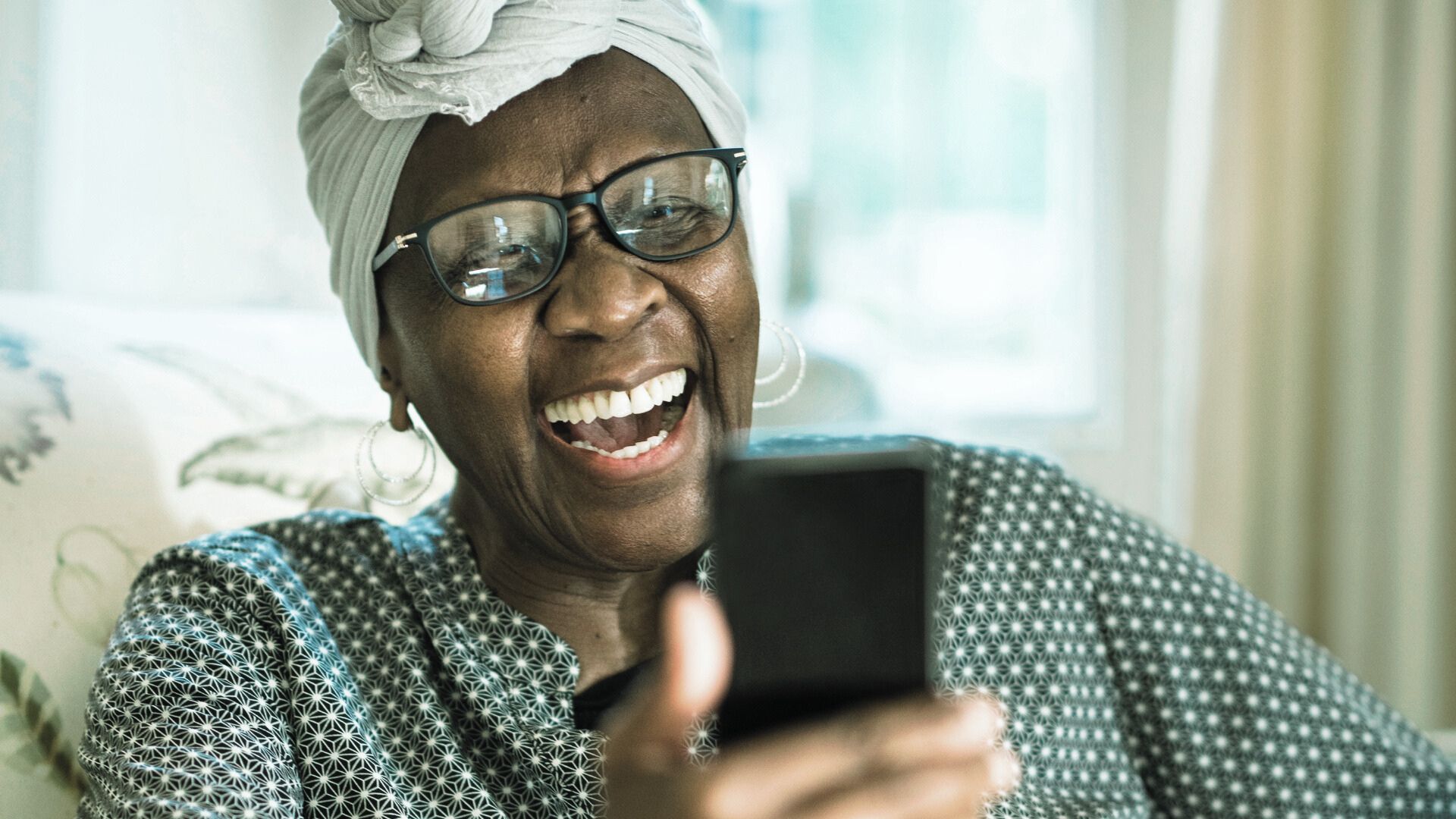 elderly woman watching a cellphone and laughing