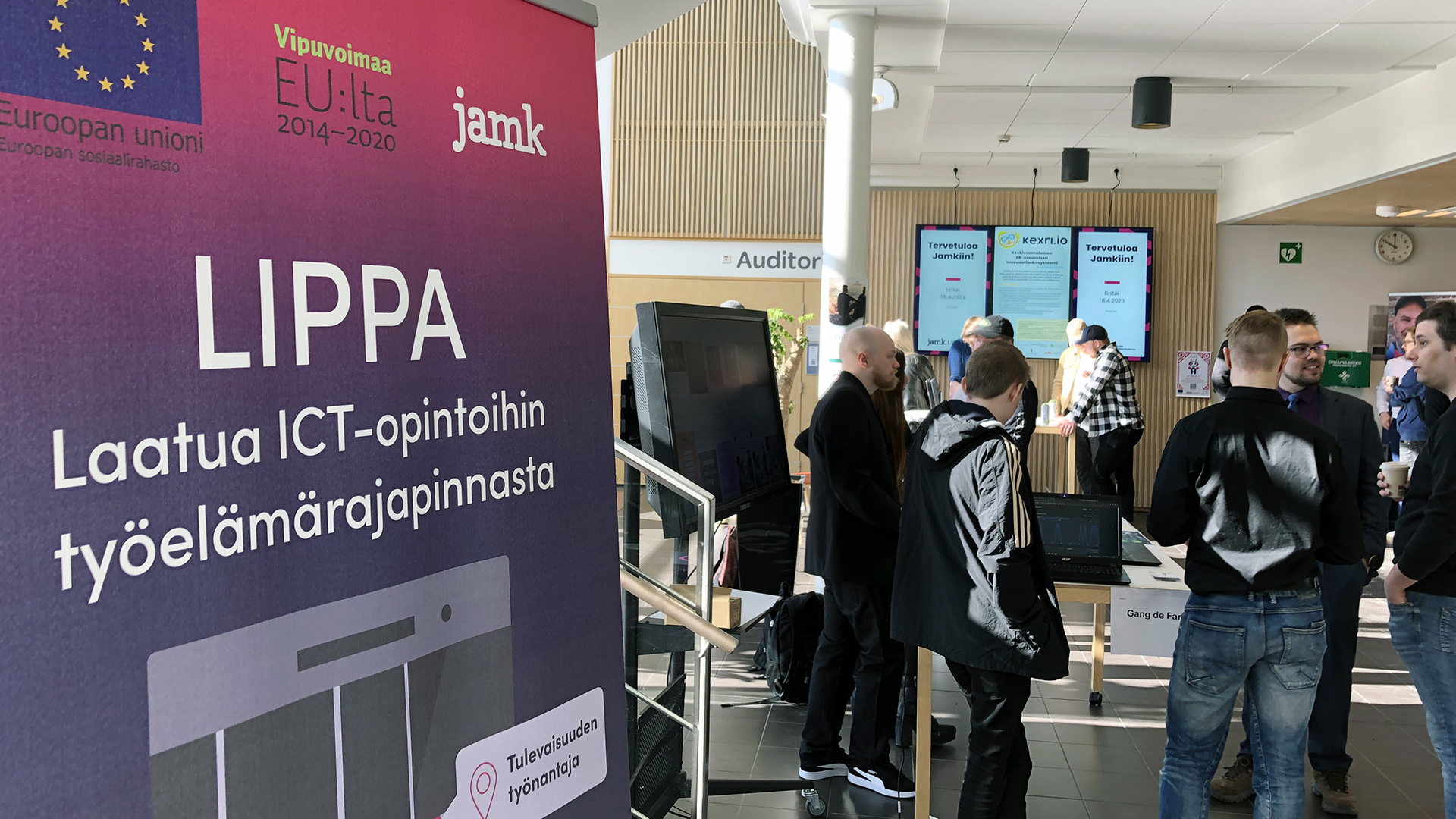 LIPPA-projektin rollup EU-logoilla edustalla ja taustalla ammattikorkeakoulun aulassa opiskelijoita tapahtumassa.