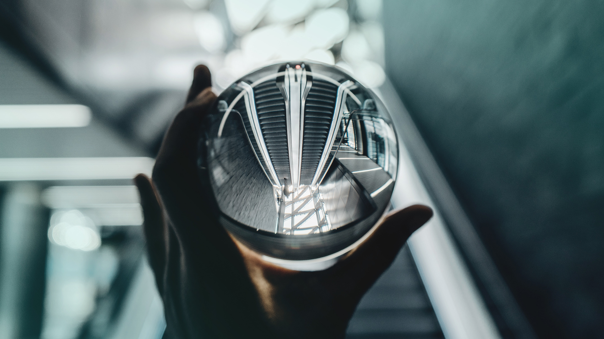 Käsi pitelee lasipalloa, jonka läpi näkyy portaikko.