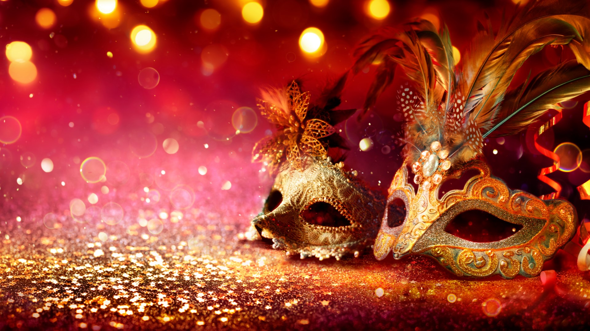Two golden venetian masquerade masks with feathers on a sparkling golden background