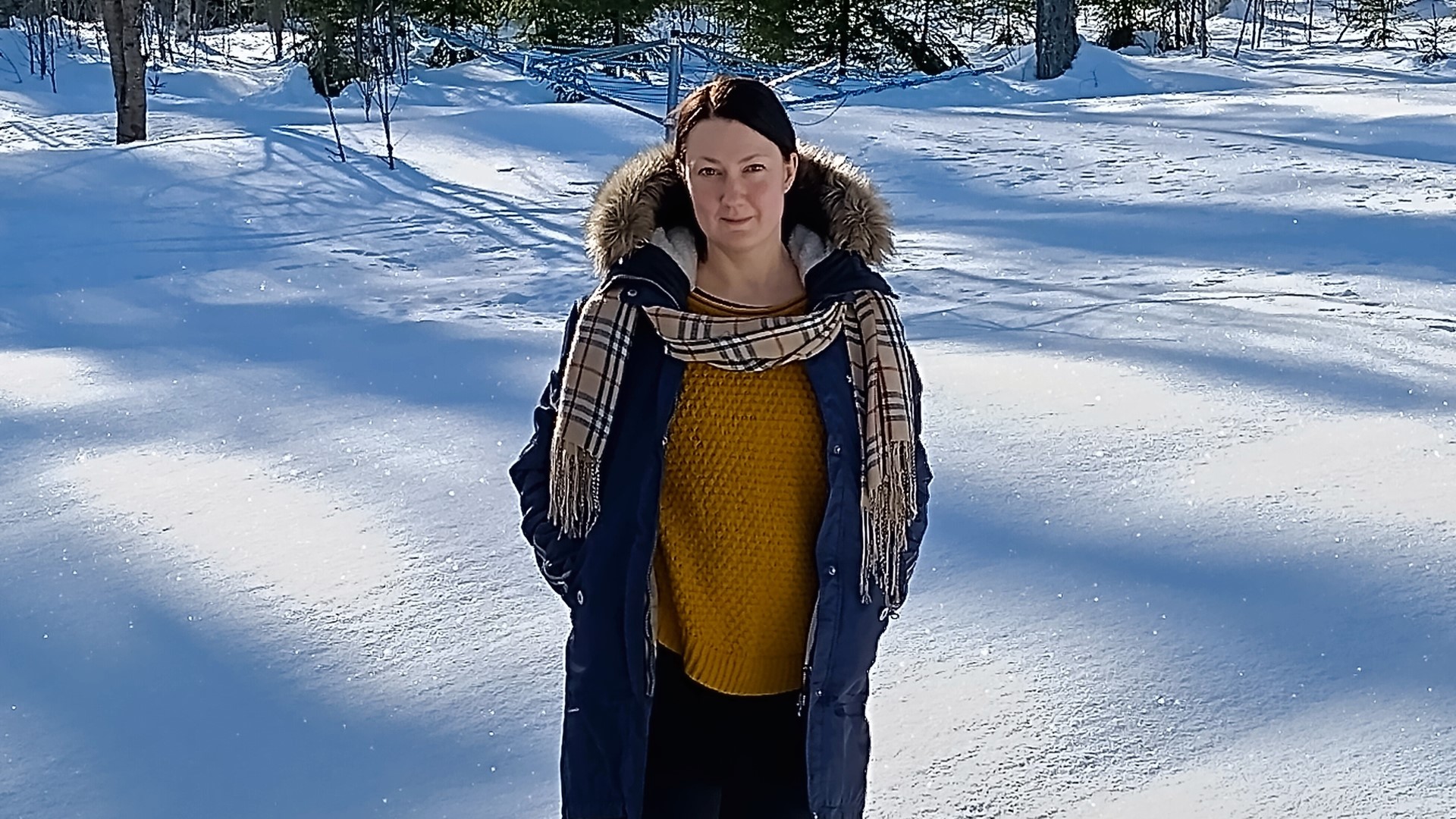Kirsi Ruukki-Viinikka seisoo aurinkoisessa lumihangessa ja katsoo suoraan kameraan