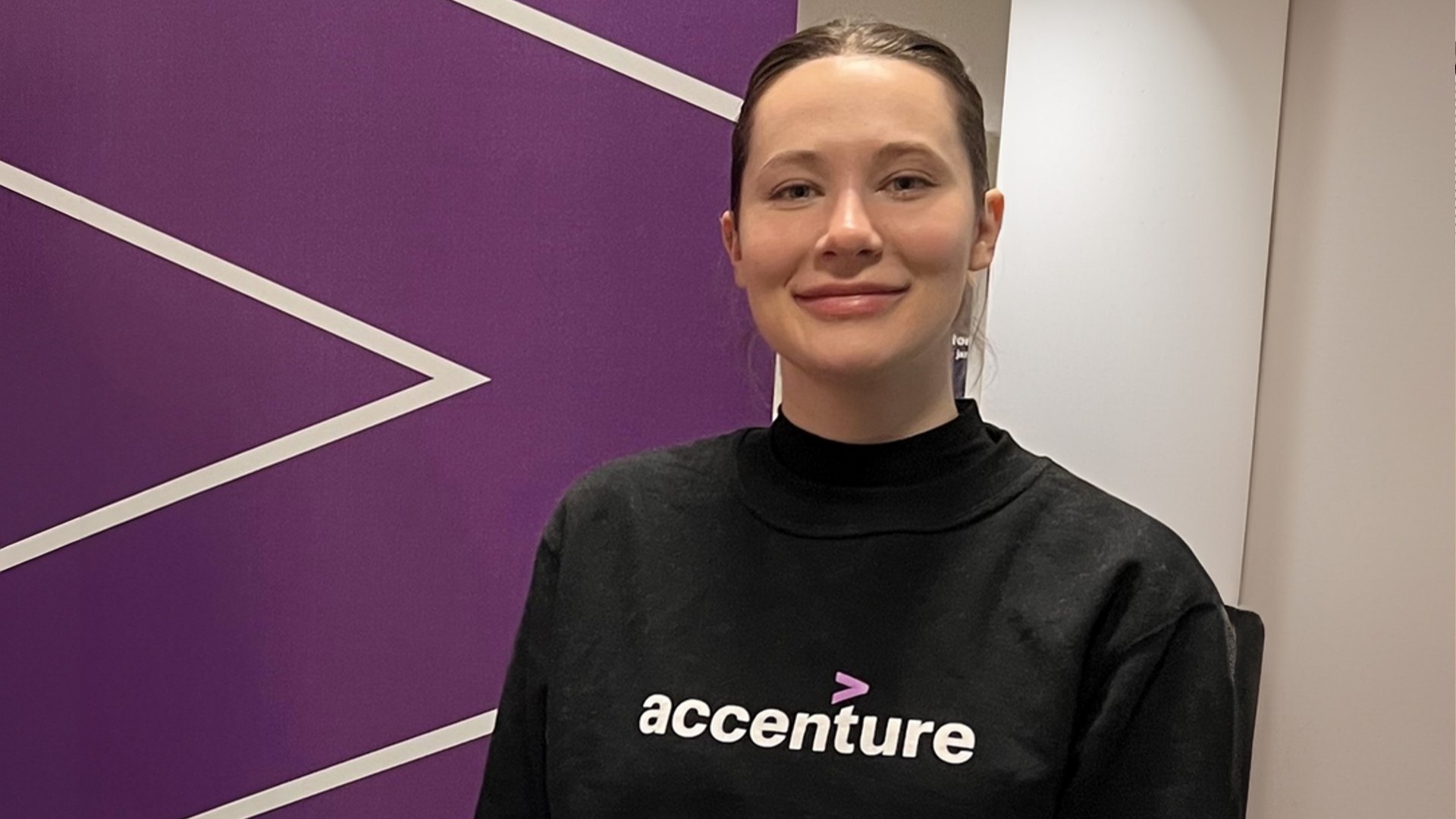 Ystävällisen näköinen nuori nainen hymyilee kameraan.