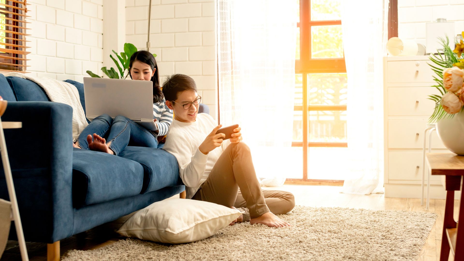 kaksi henkilöä käyttämässä kannettavaa tietokonetta ja puhelinta