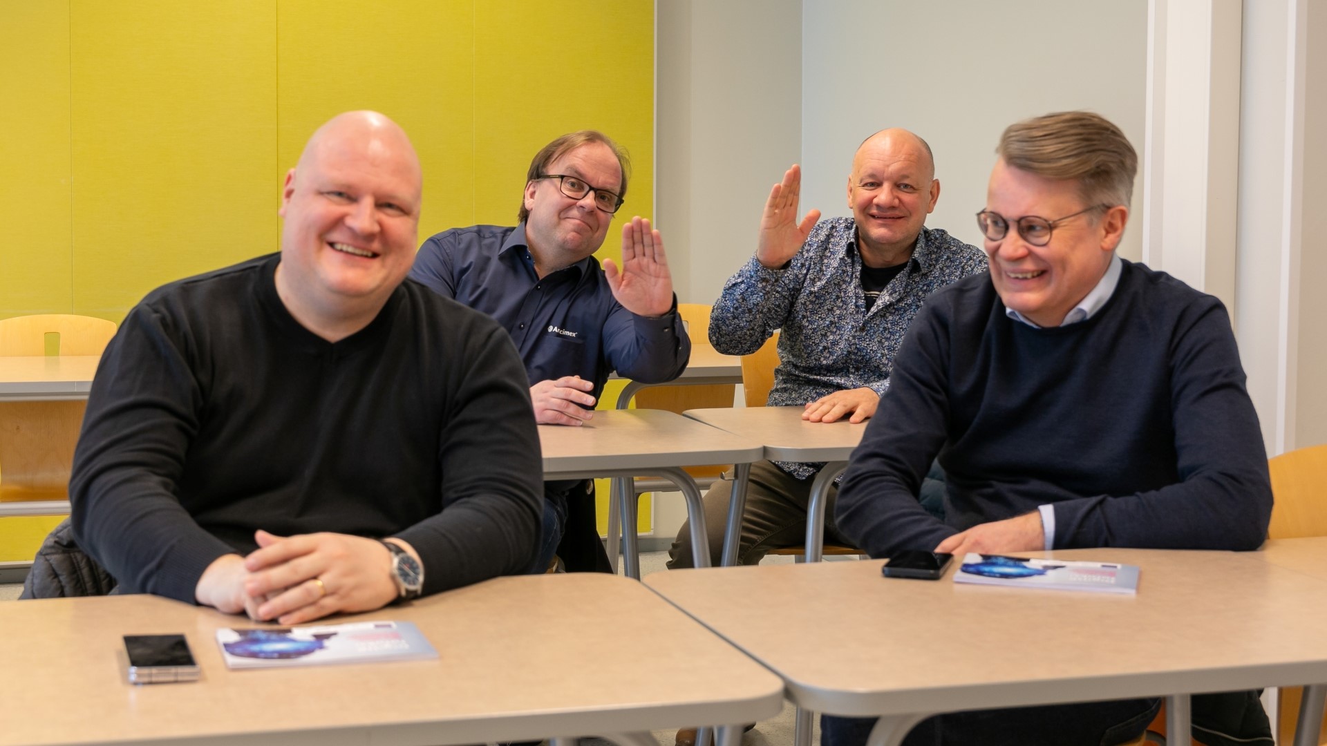 Neljä Jamkin alumnia istuu pulpeteissa ja viittaa