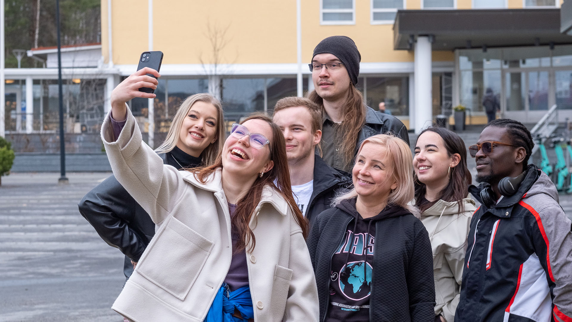 Opiskelijoita ottamassa ryhmäkuvaa pääkampuksen edessä.