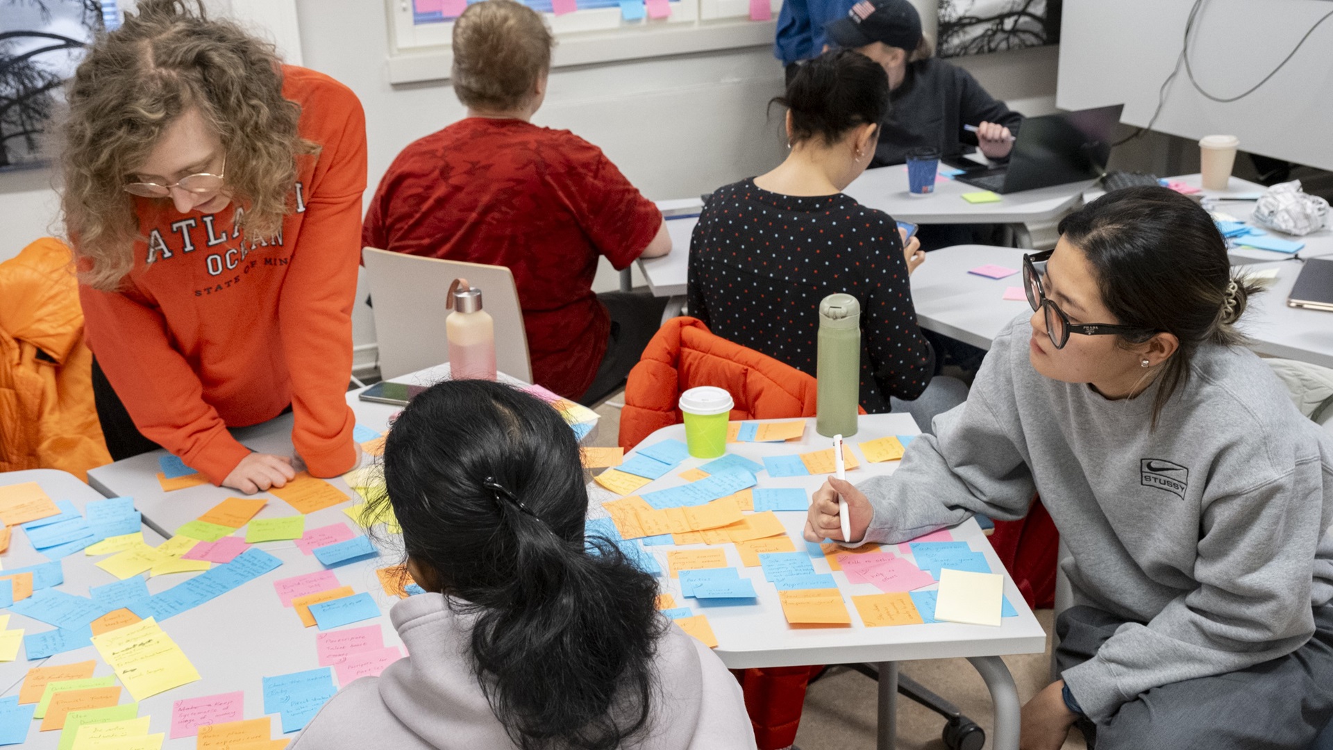 Kuvassa post-it lappuja ja opiskelijoita