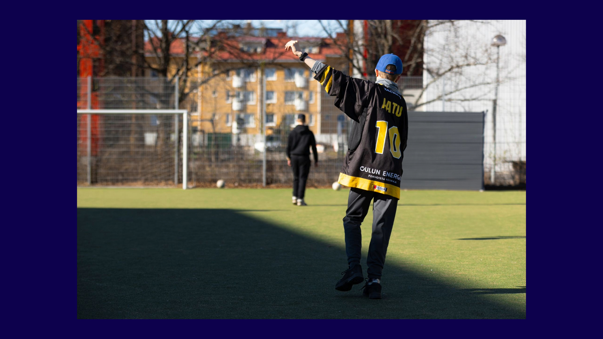 Henkilö pelaamassa jalkapalloa selin kameraan. Hänen vasen kätensä on nostettu ylös ja siinä on liikemittari.