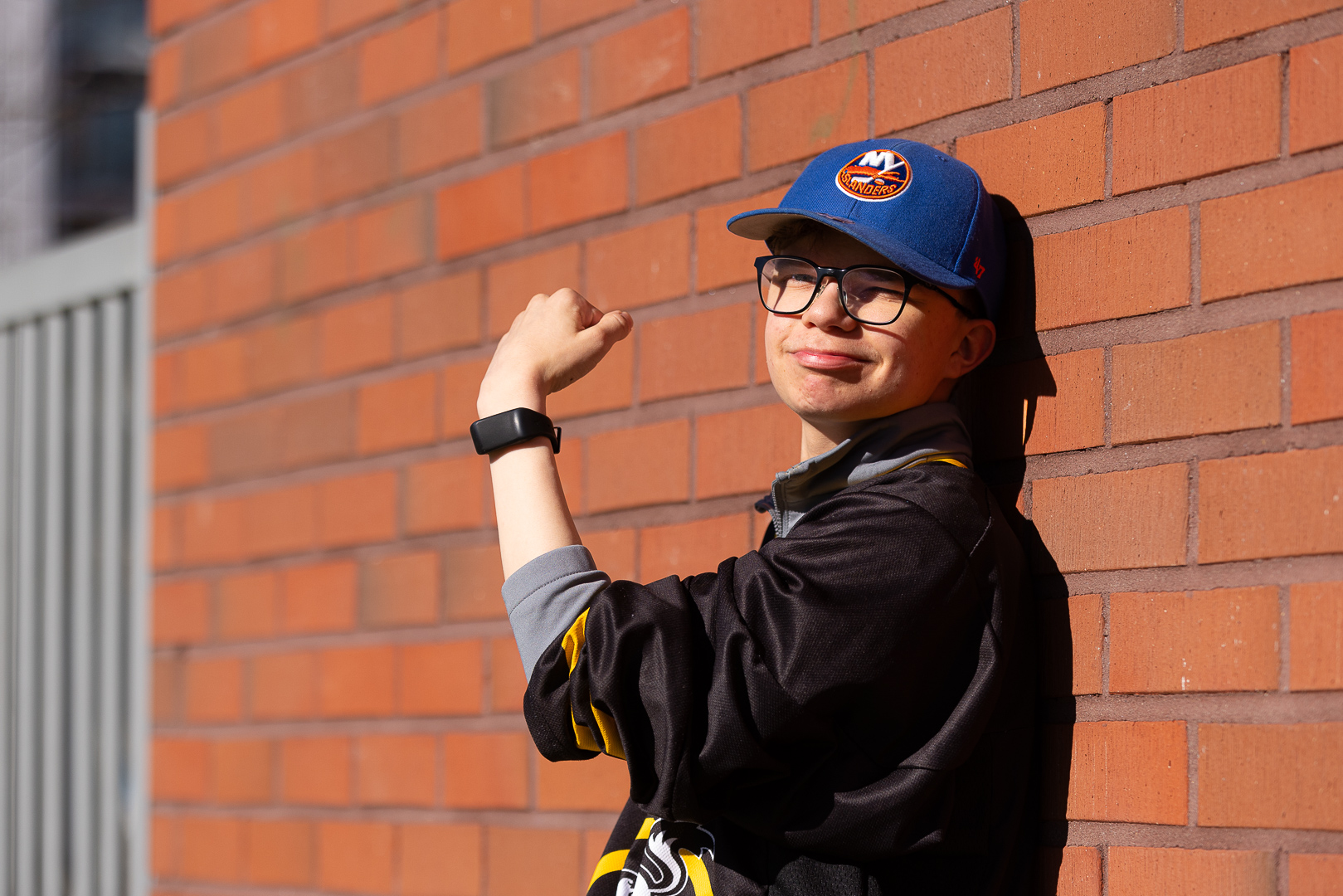 Henkilö katsoo kameraan hymyillen. Hän on nostanut kätensä koukkuun eteensä, ranteessa on liikemittari.