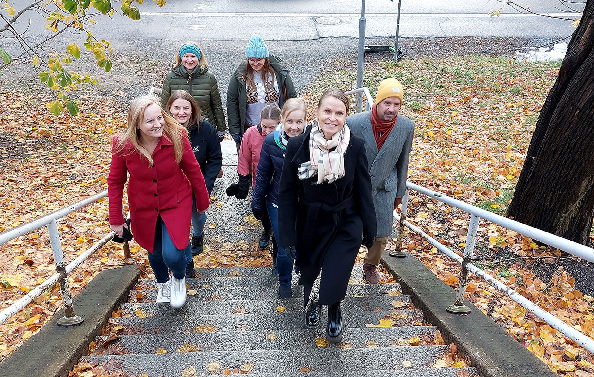 Henkilöitä nousee rappusia syksyisessä kaupungissa.