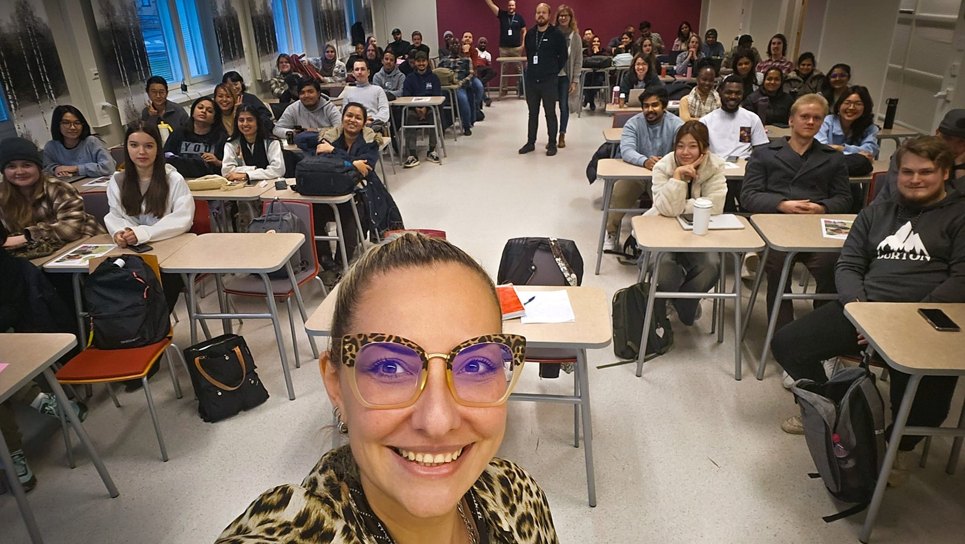 Kuvassa toimeksiantaja Rositsa Röntynen luokkahuoneessa jossa myös opiskelijoita sekä Jamkin henkilökuntaa