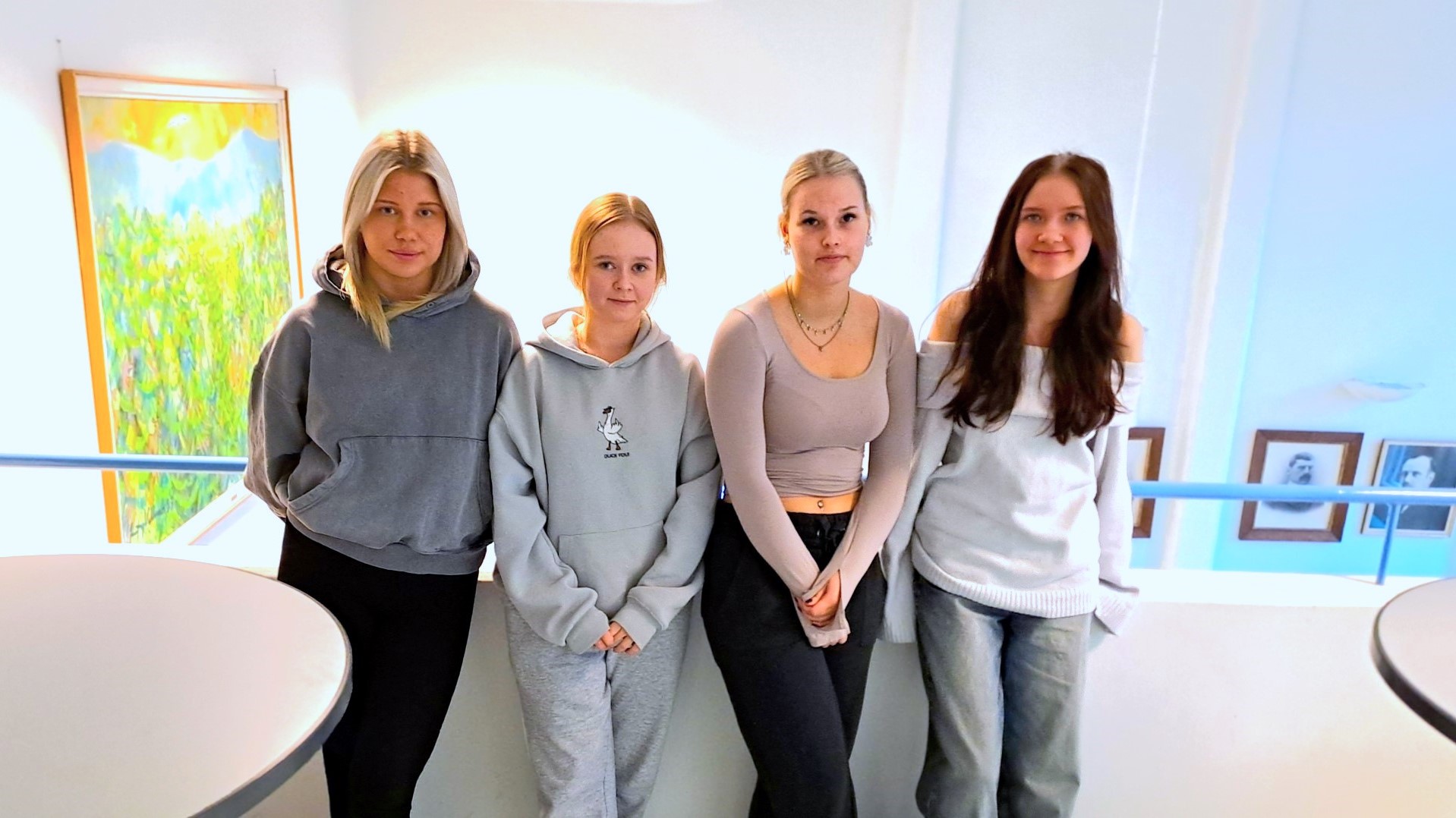 Neljä lukiolaista nojailee kaiteeseen ja katsoo suoraan kameraan