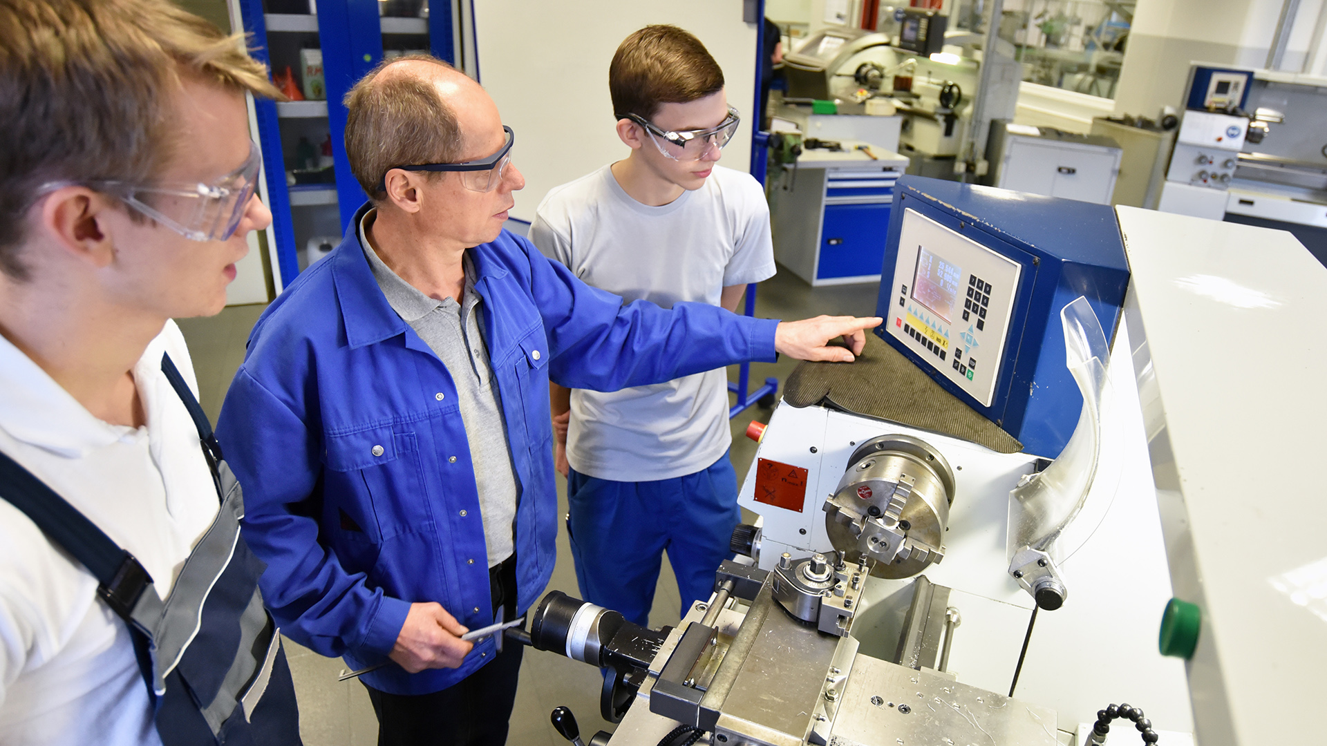 Kaksi ammatillisen koulutuksen opiskelijaa ja ohjaaja työpaikalla oppimassa.