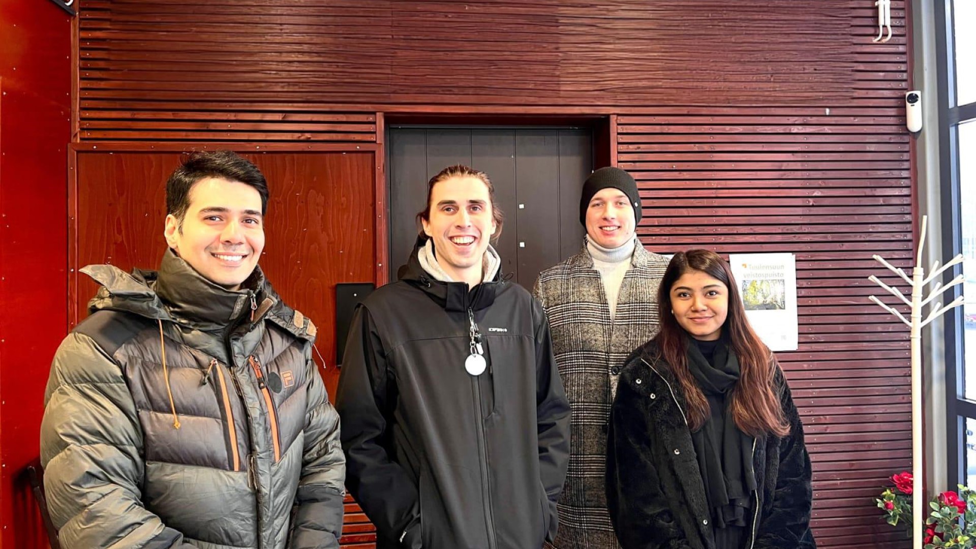 A group of international students standing in front of a building in the winter, looking happy