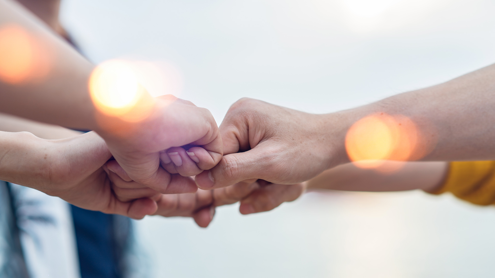 Kimalluksia ja kuvan keskellä kohtaavat nyrkissä olevat kädet.