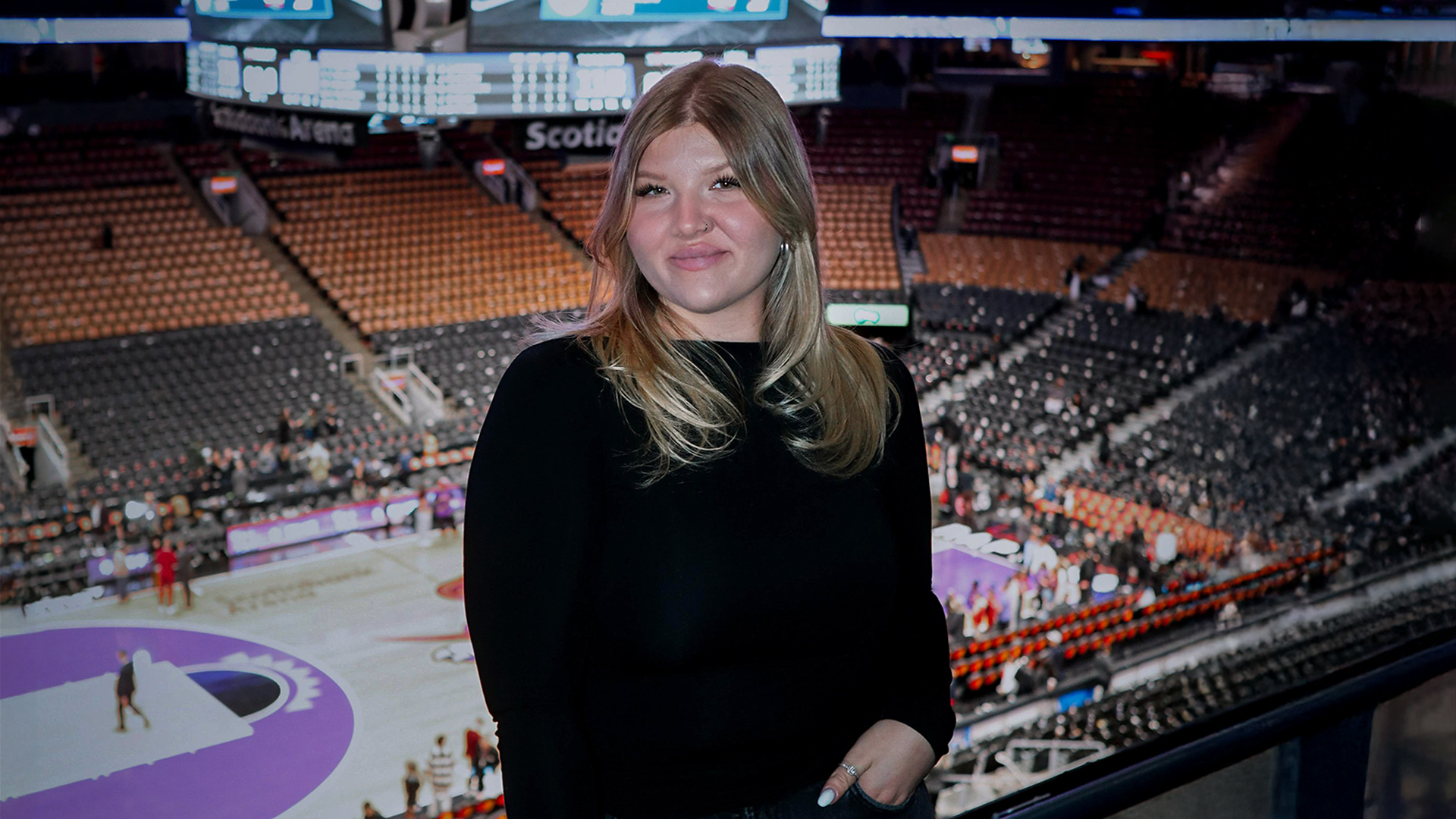 Hymyilevä opiskelija koripallohallissa.