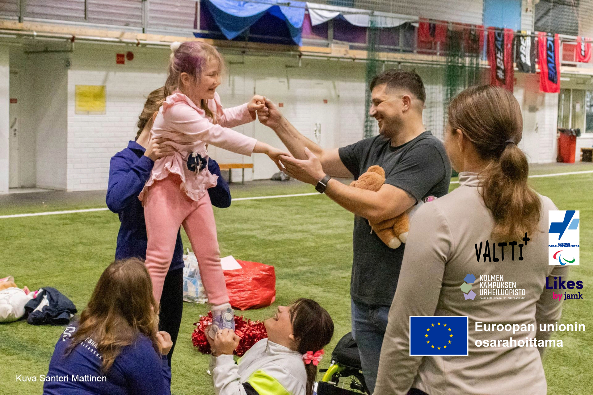 Henkilö pitää lasta kädestä urheilukentällä sisähallissa.