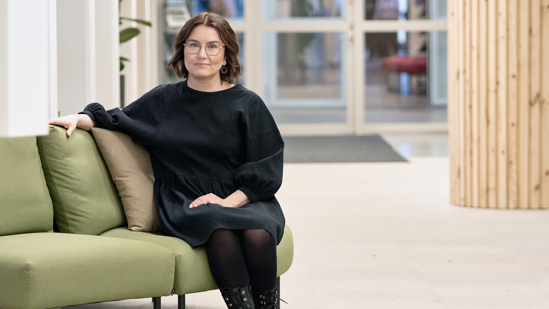 Kaisa Malinen istumassa vihreällä sohvalla.