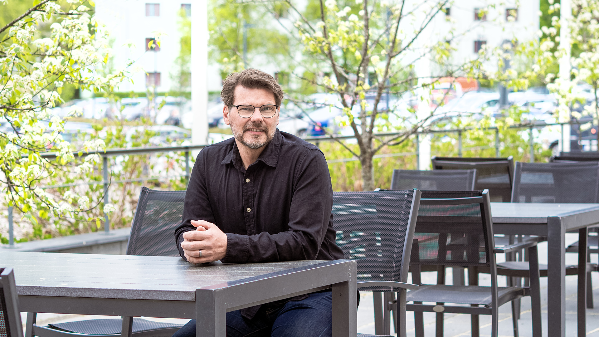 Mies istuu ulkona terassipöydän ääressä.