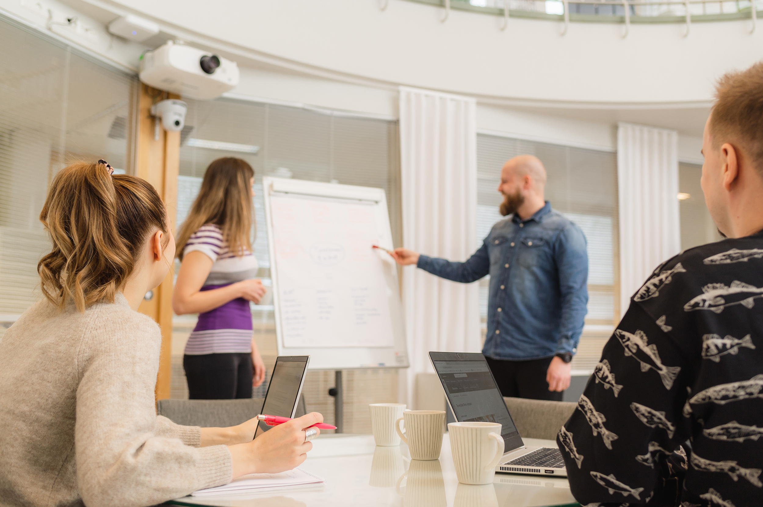 Four people in a classroom looking at a whiteboard