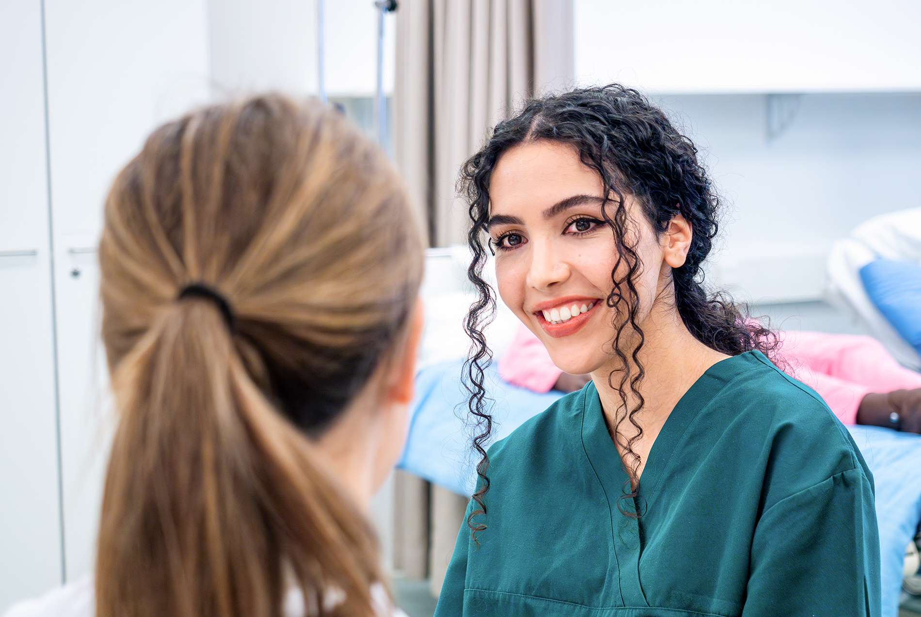 Assumed woman on nurses clothes smiling to another person.