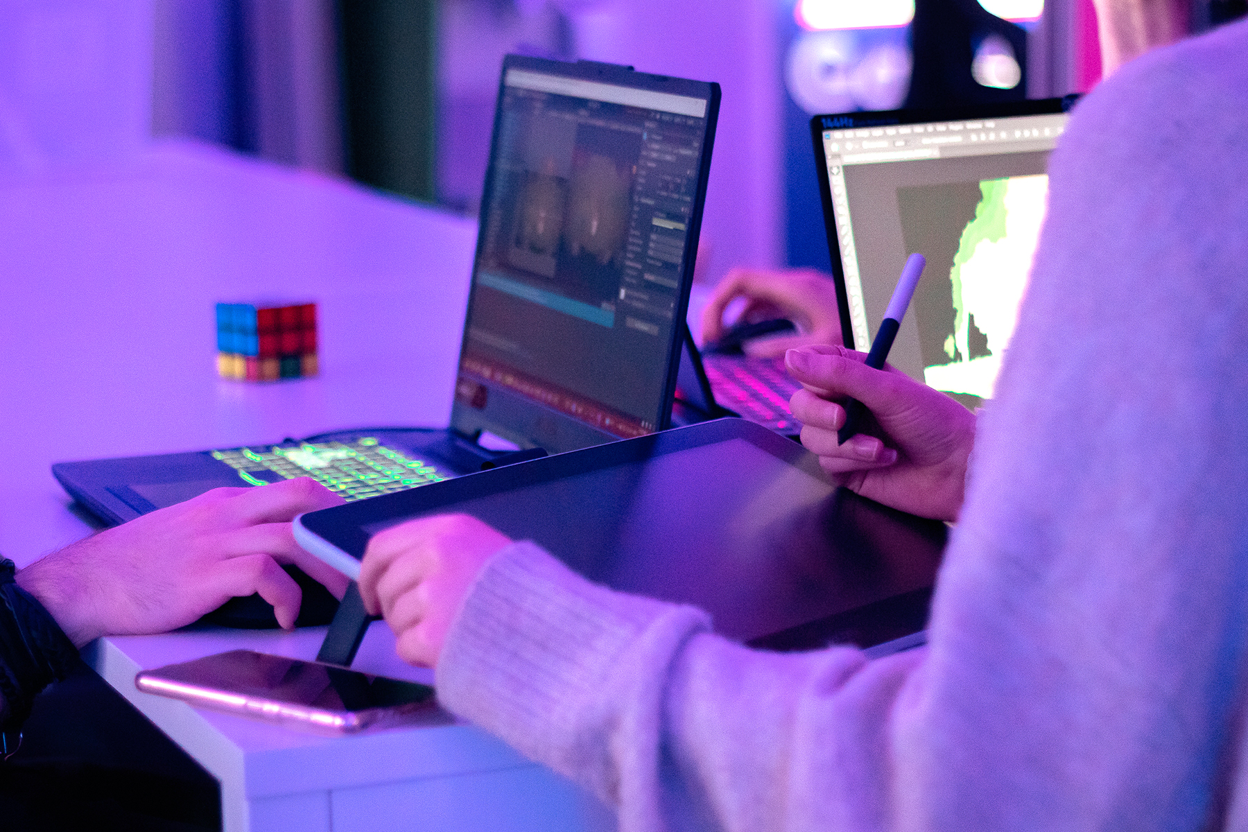 Laptops and drawing tablet with hands of people using them.