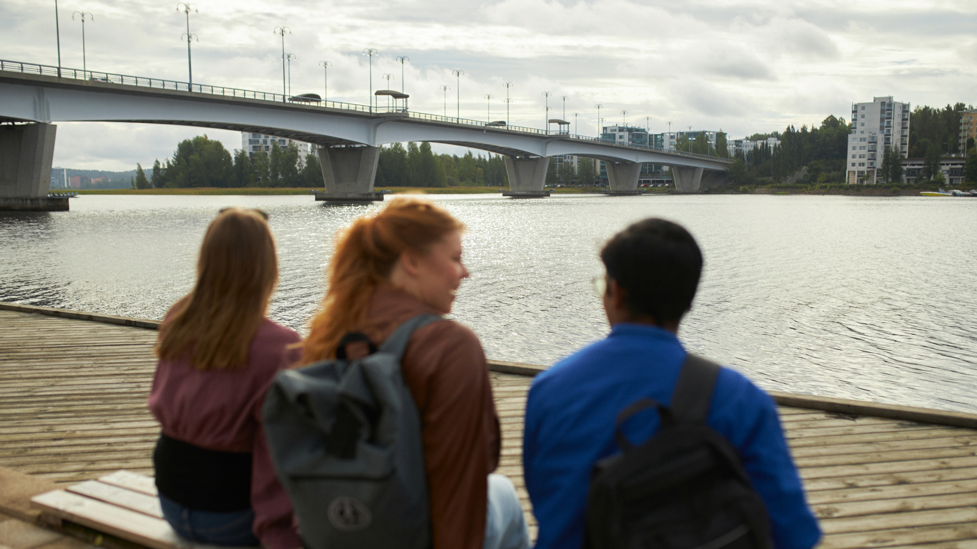 Three people looking at Kuokkala brigde in the distance in a cloudy summer day