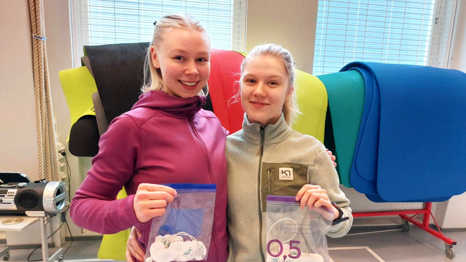 Kaksi henkilöä koulun liikuntasalissa.