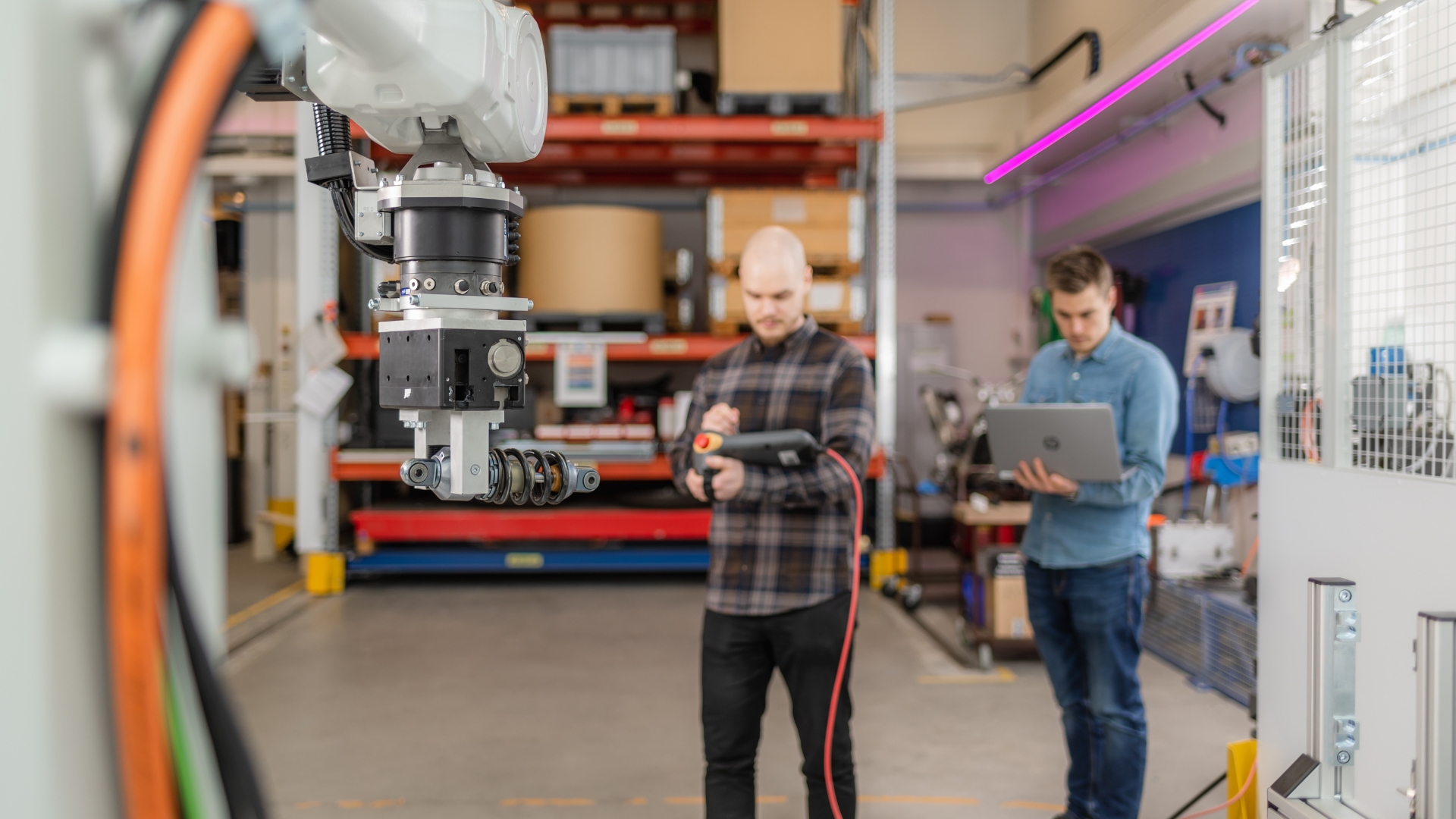 Kaksi henkilöä työskentelemässä teollisuusrobotin parissa