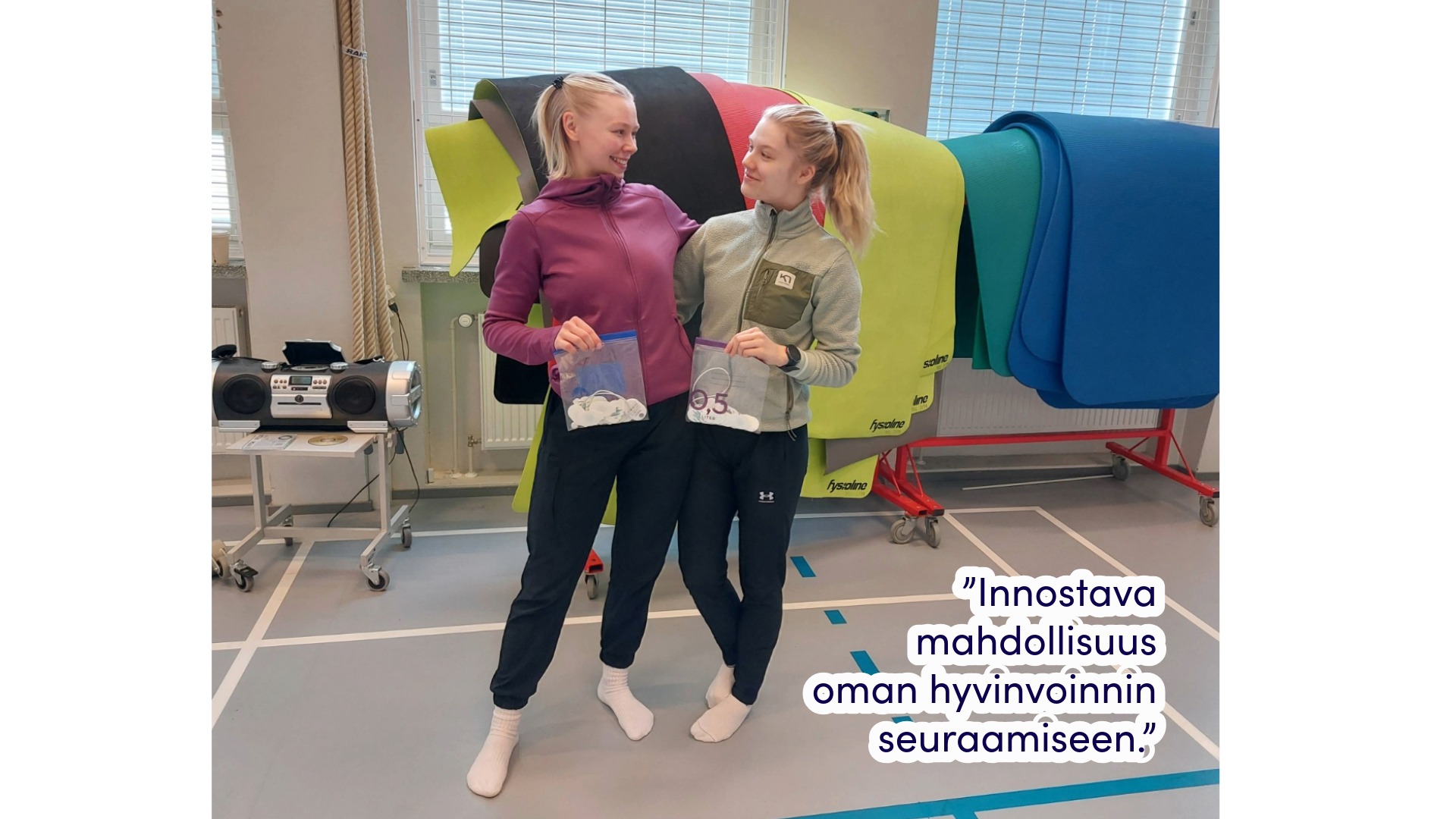 Kaksi henkilöä seisoo liikuntasalissa.