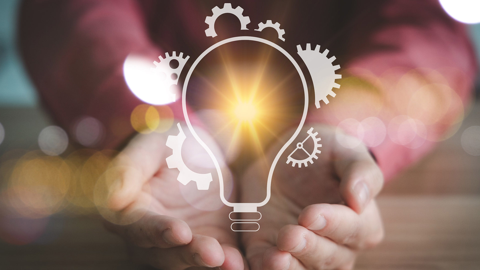 Käsien päällä piirretty hehkulamppu ja kimalluksia.