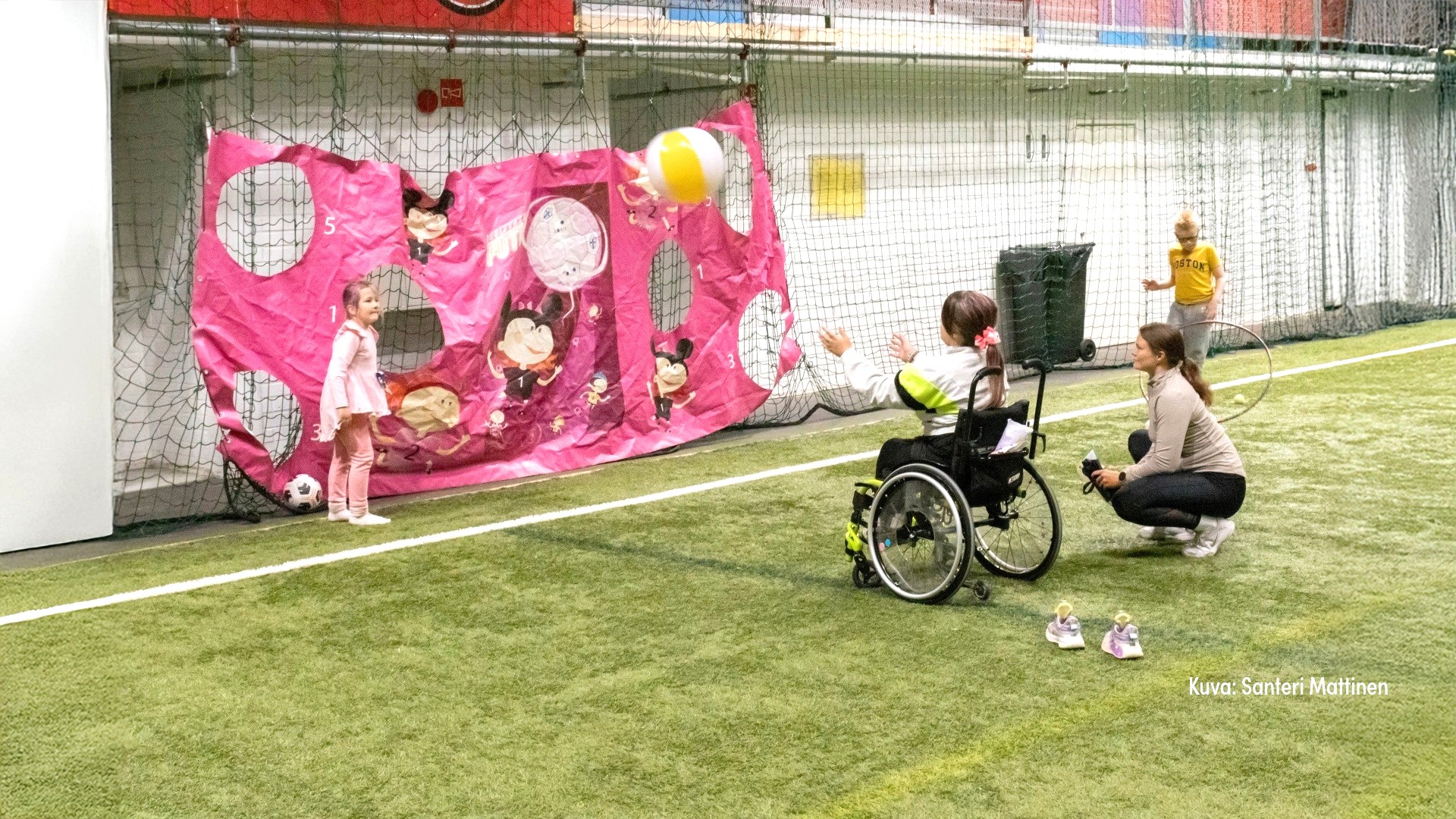 Lapsi istuu pyörätuolissa ja heittää palloa. Kuva Santeri Mattinen.