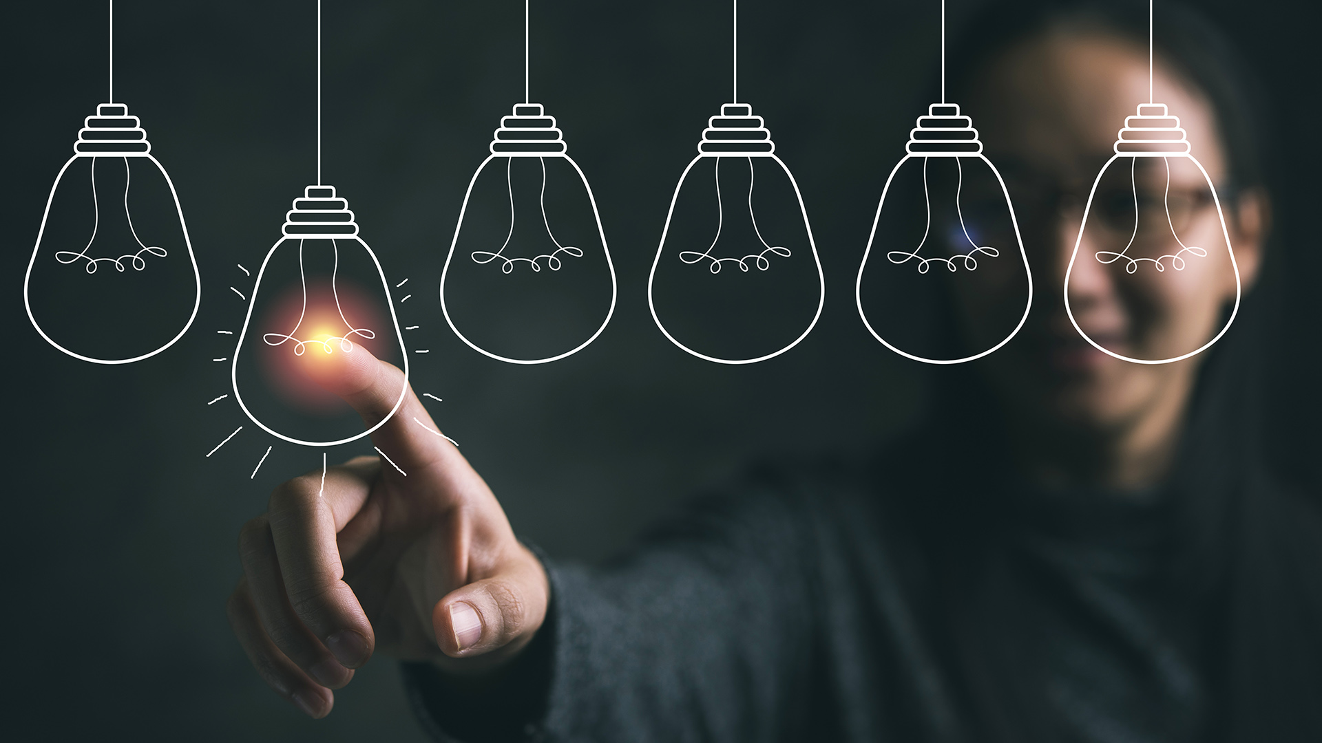 Henkilö osoittaa piirrettyä hehkulamppua.