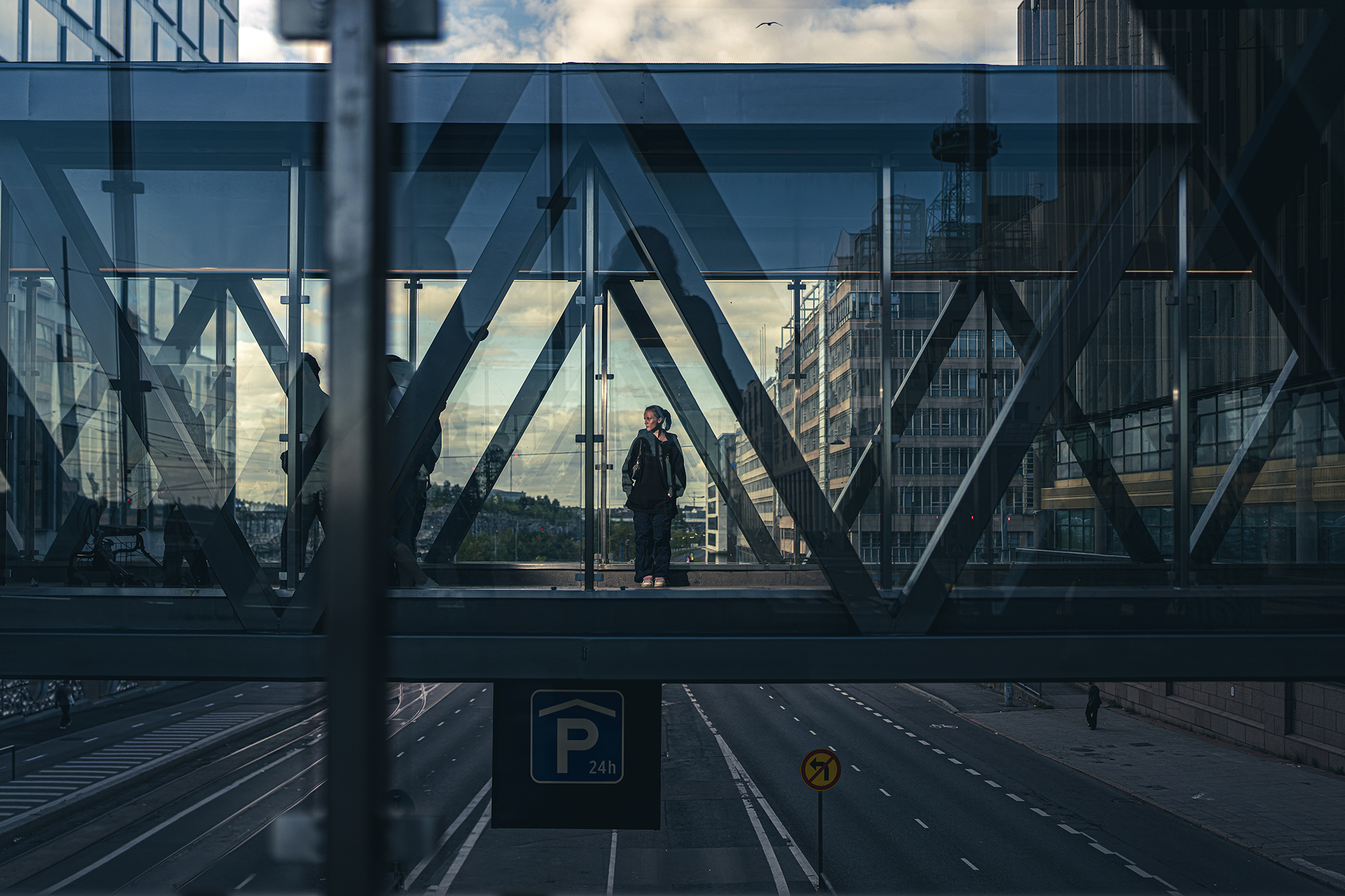 Nuori ihminen seisomassa lasisella ylikulkusillalla