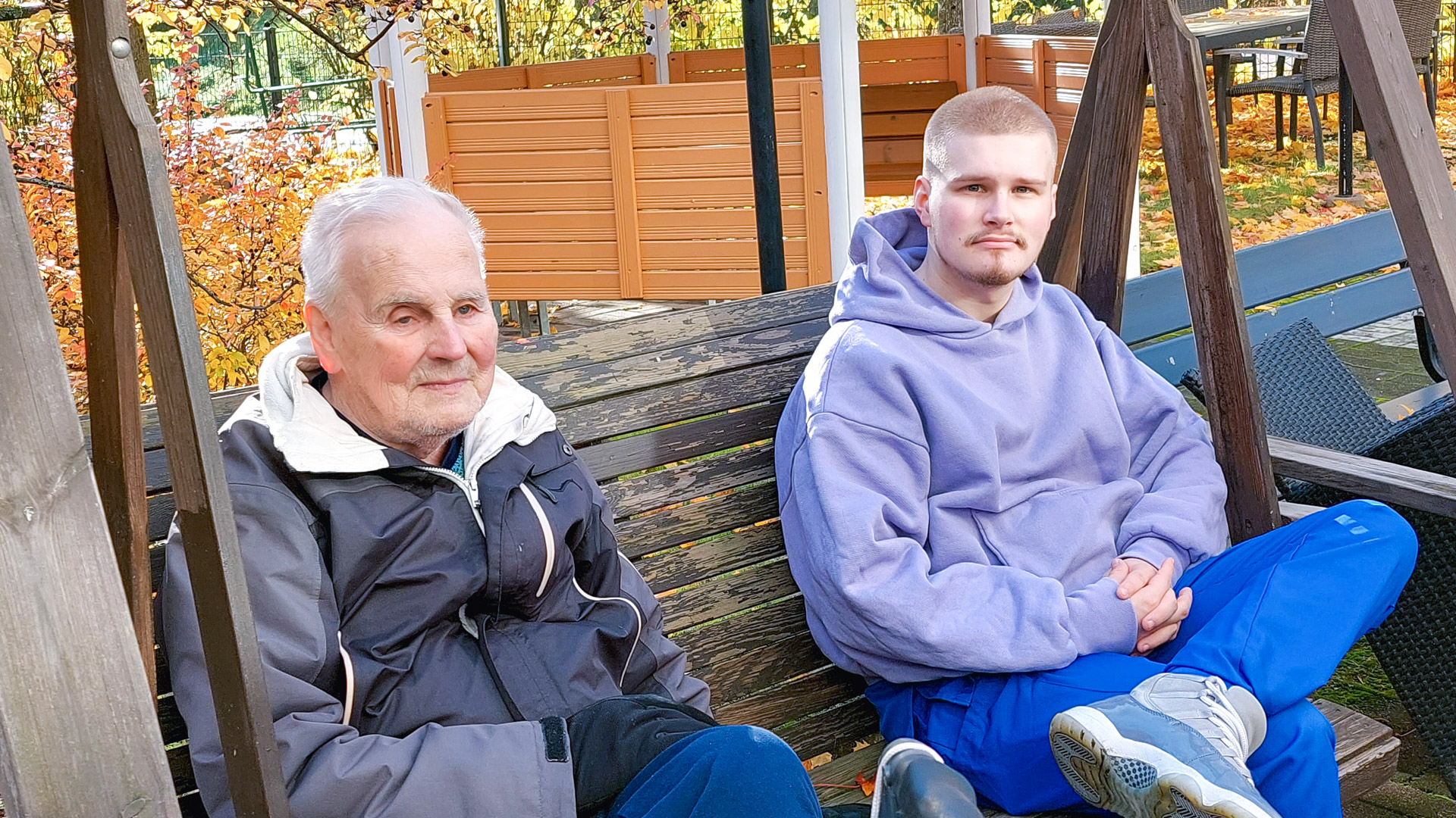 Palvelutalon asukas ja sairaanhoitajaopiskelija istumassa pihakeinussa.