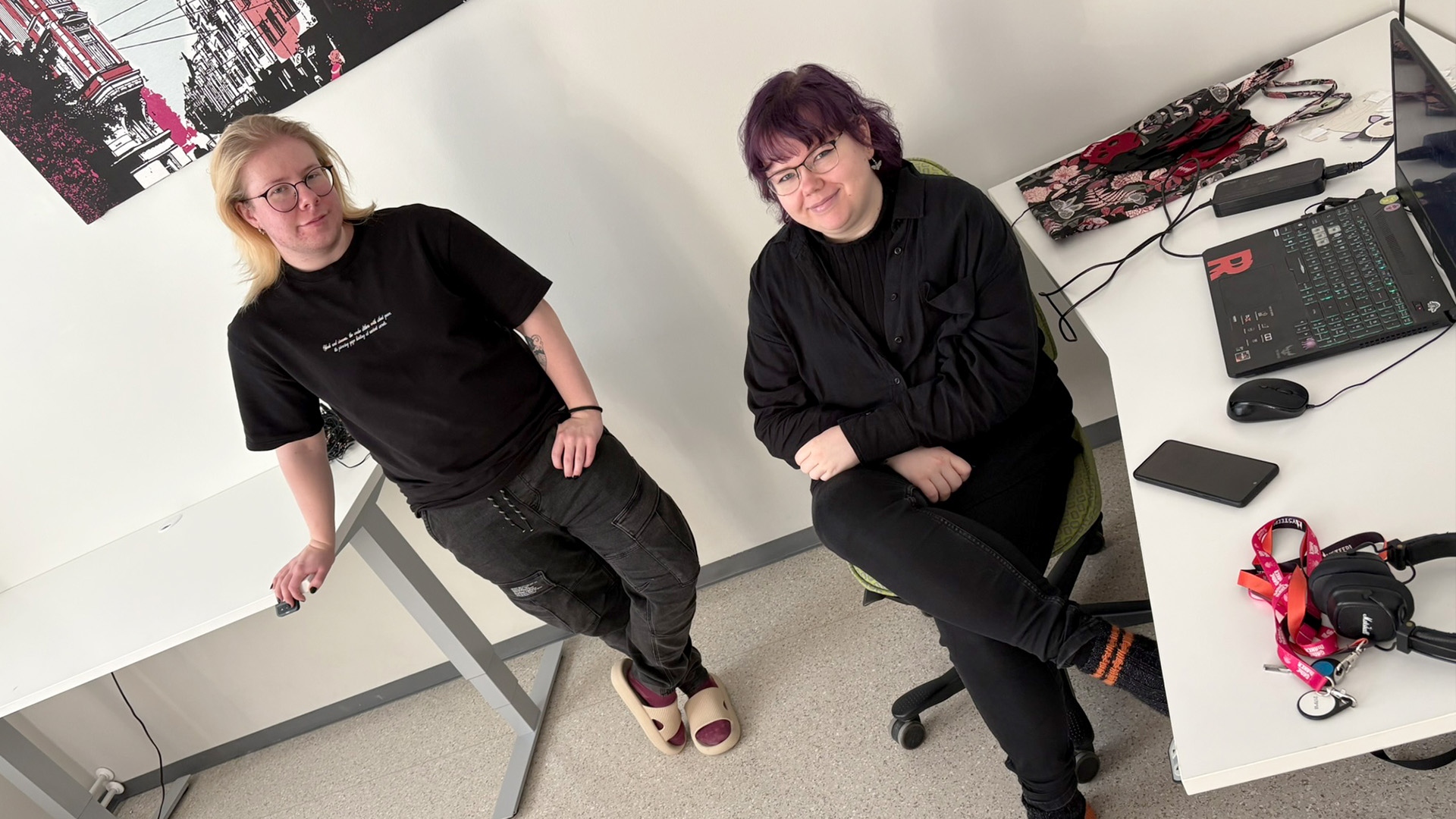 Saku Raitanen and Milla Koivuniemi are sitting at their office desks and watching into the camera.