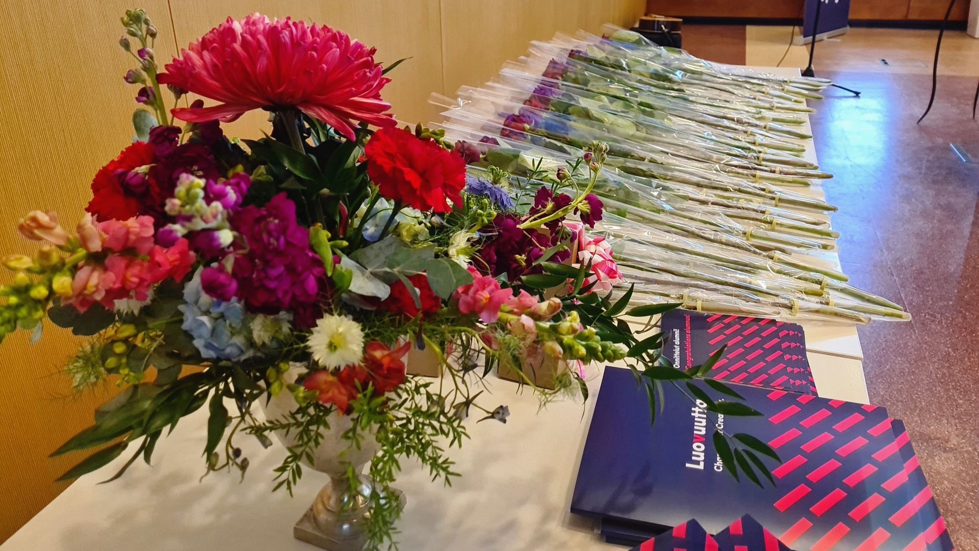 Kukkakimppu ja ruusuja sekä valmistuneiden opiskeljoiden todistuskansioita