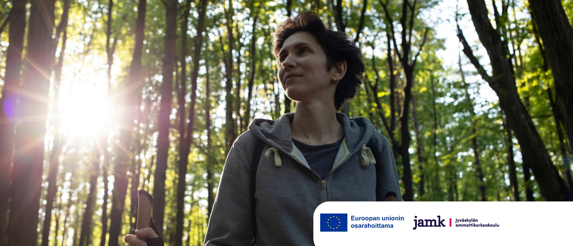 Nainen kävelee keväisessä metsässä. Aurinko paistaa puiden oksien välistä. Oikeassa alareunassa on Euroopan unionin osarahoittama -logo ja Jyväskylän ammattikorkeakoulun logo.