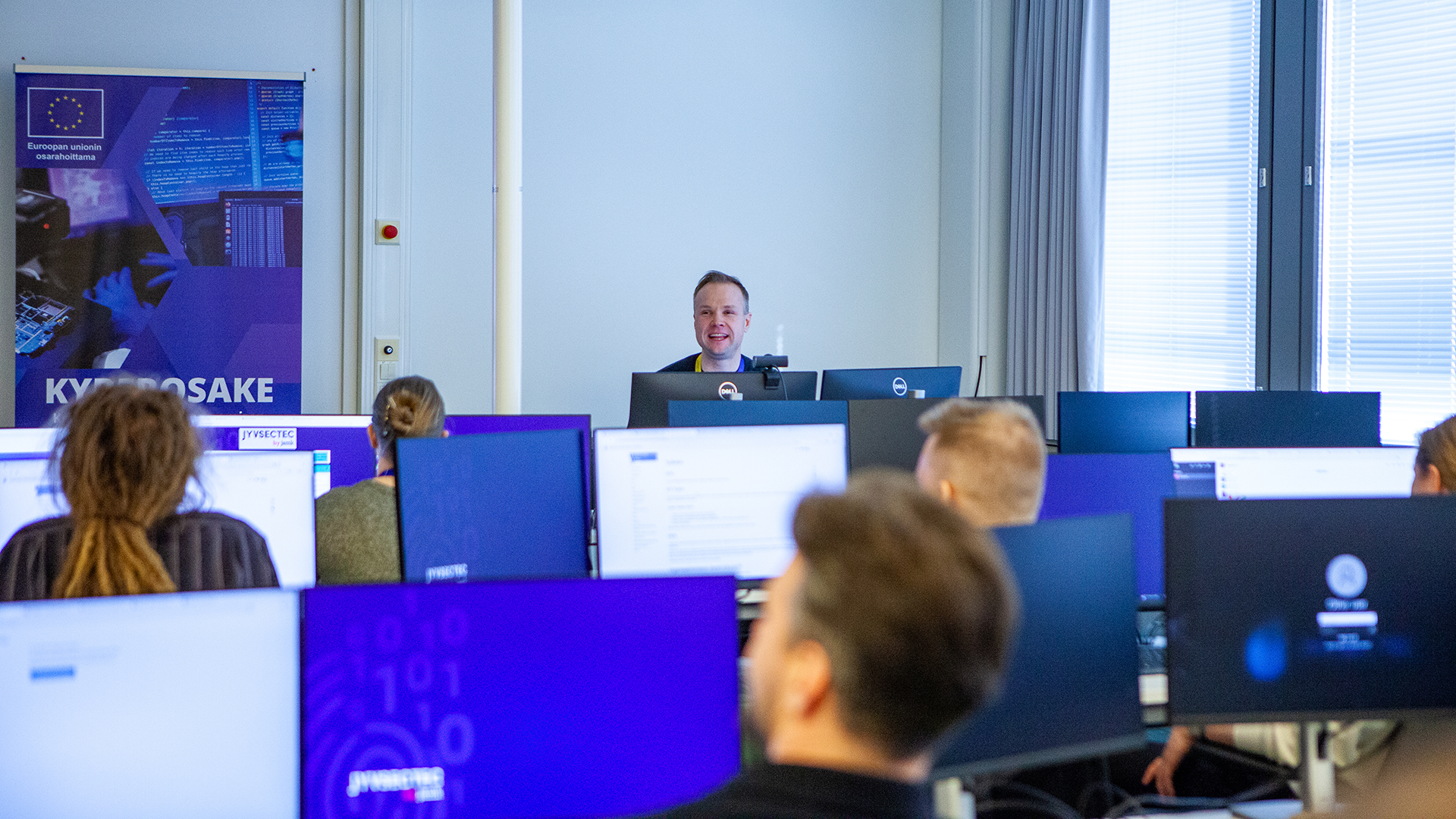 Ihmisiä näyttöjen äärellä JYVSECTECin tilannehuoneessa